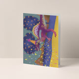 Dubbelgevouwen A6-kaart van Studio LilaLine met op de voorkant een feestelijke illustratie van een spinosaurus – de dino draagt een feesthoedje en schiet een party popper af, terwijl confetti alle kanten op vliegt. De kleuren zijn vrolijk en knallend, perfect voor een verjaardagskaart met humor en energie. De binnenkant is leeg en biedt ruimte voor een persoonlijke boodschap.