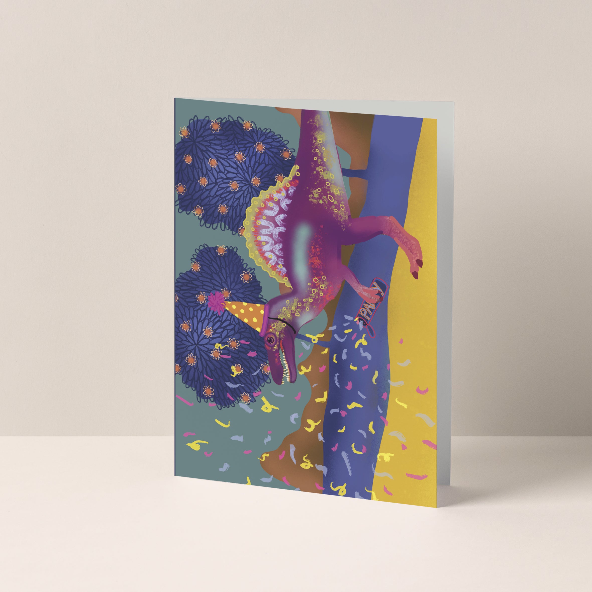 Dubbelgevouwen A6-kaart van Studio LilaLine met op de voorkant een feestelijke illustratie van een spinosaurus – de dino draagt een feesthoedje en schiet een party popper af, terwijl confetti alle kanten op vliegt. De kleuren zijn vrolijk en knallend, perfect voor een verjaardagskaart met humor en energie. De binnenkant is leeg en biedt ruimte voor een persoonlijke boodschap.
