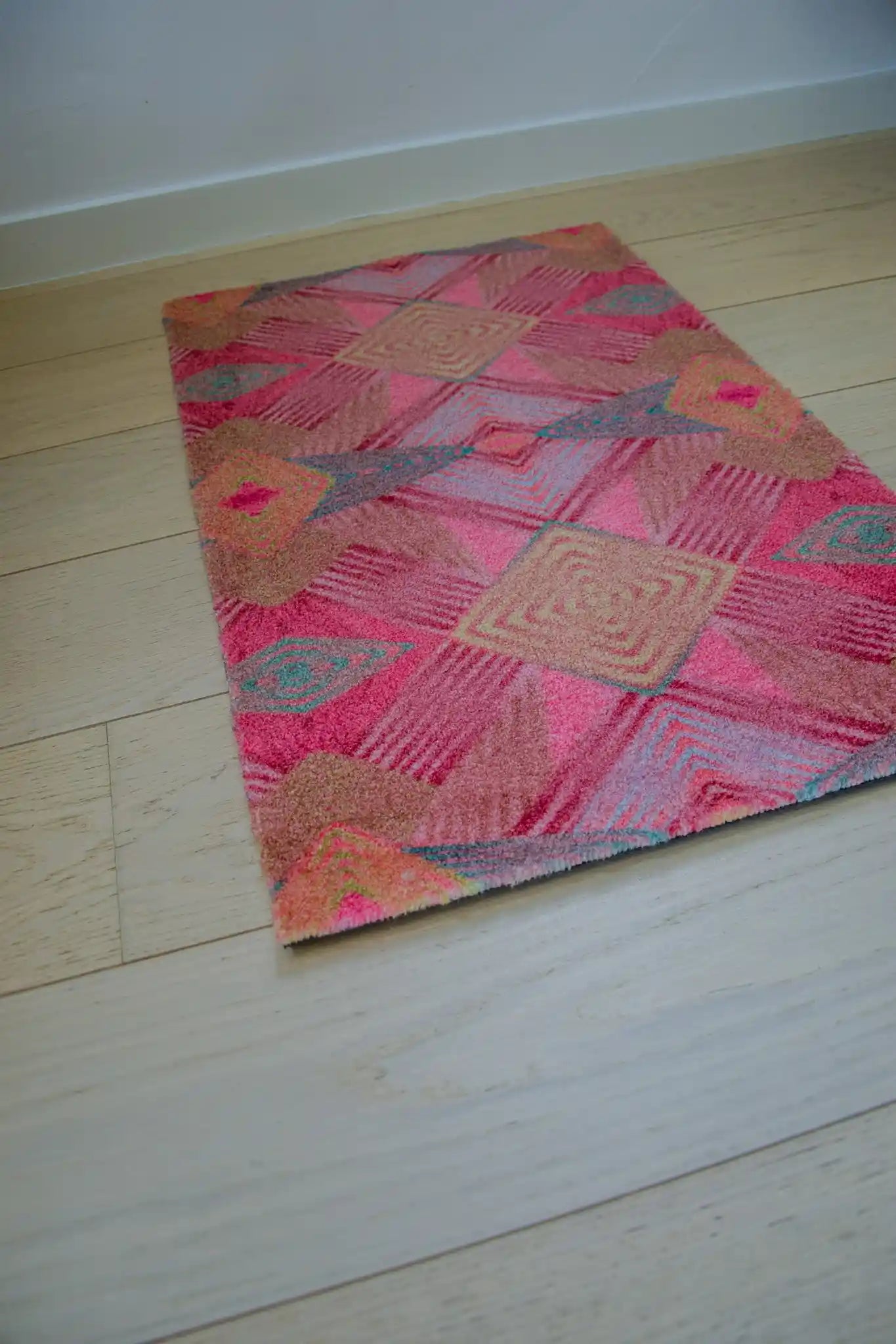Zachte, goed absorberende badmat van Studio LilaLine met een speels diamantpatroon in roze, groen en mosterdgeel – de grafische vormen wisselen elkaar af in een ritmisch patroon dat doet denken aan een retro mozaïek. De kleuren zorgen voor een vrolijke en warme sfeer in de badkamer. De mat voelt heerlijk zacht onder de voeten.