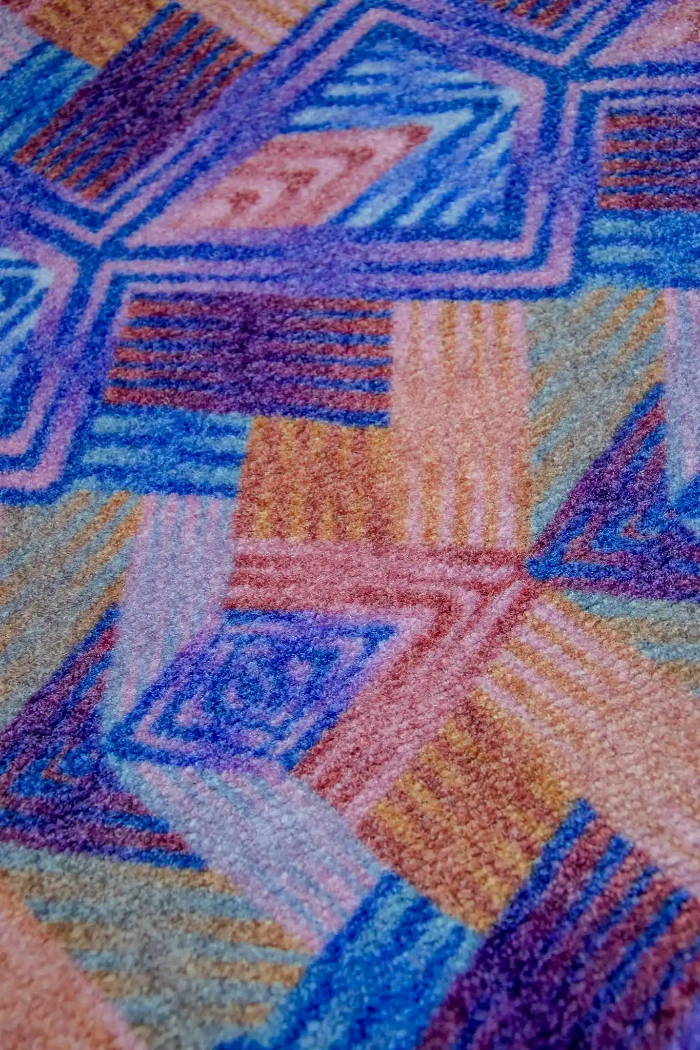 Zachte, goed absorberende badmat van Studio LilaLine met een grafisch diamantpatroon in paarse en roze tinten – de vormen zijn ritmisch en speels, met een vrolijke retro-uitstraling. De kleuren zorgen voor een warme, levendige sfeer in de badkamer. Heerlijk comfortabel onder je voeten na het douchen.