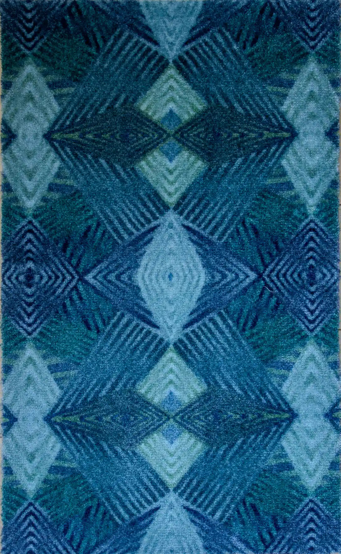 Zachte, waterabsorberende badmat van Studio LilaLine met een grafisch diamantpatroon in tinten petrol, blauw en groen – het ontwerp bestaat uit ritmische lijnen en geometrische vormen die samen een kalme, frisse uitstraling geven. De mat voelt aangenaam onder blote voeten en brengt kleur en stijl in de badkamer.
