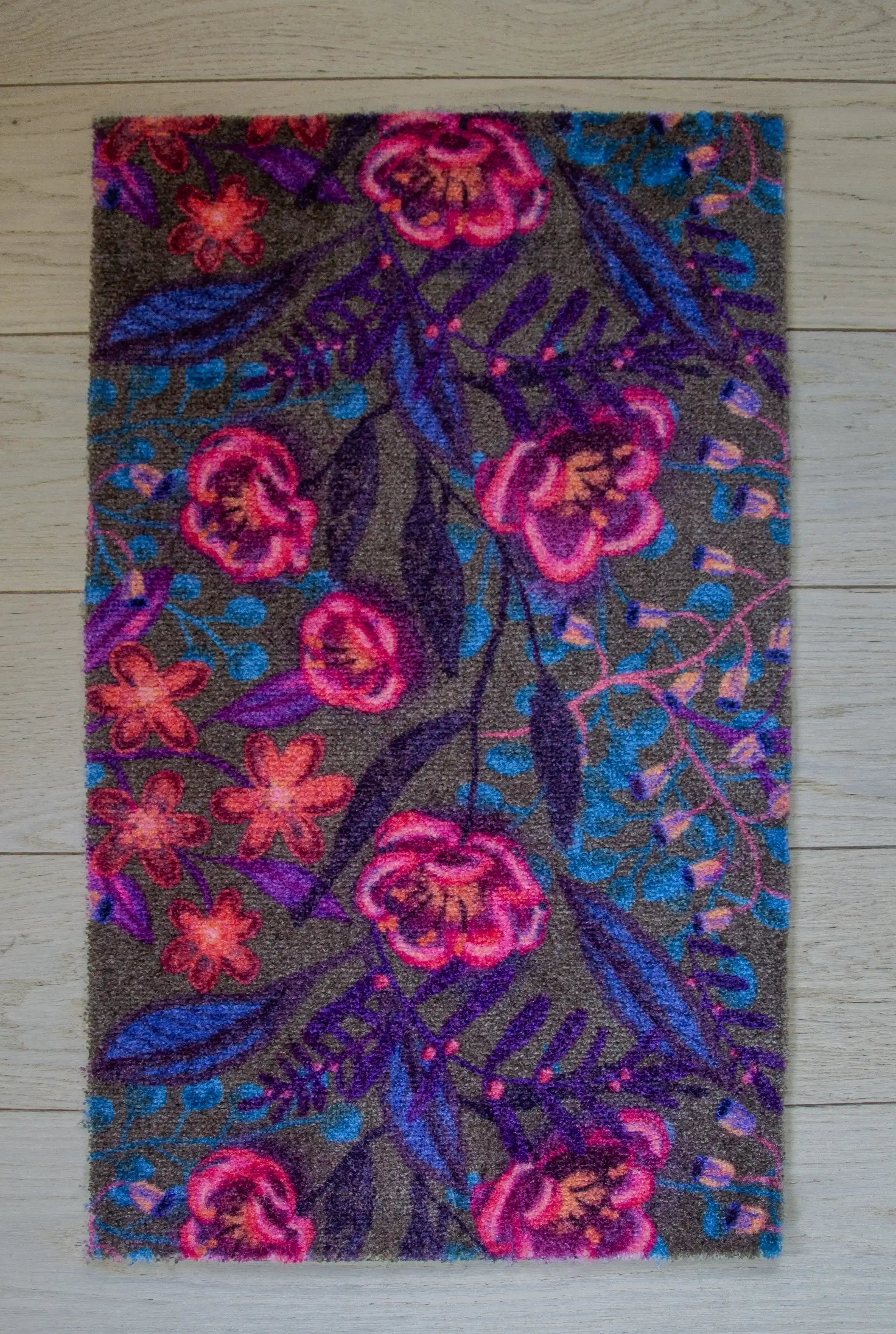 Zachte en goed absorberende badmat van Studio LilaLine met een dromerige bloemenprint in sepia, roze en blauw – het ontwerp toont sierlijke bloemvormen met een zachte, bijna vintage uitstraling. De kleuren zijn warm en rustgevend, perfect om een kalme sfeer te brengen in de badkamer. De mat voelt aangenaam en comfortabel onder je voeten.