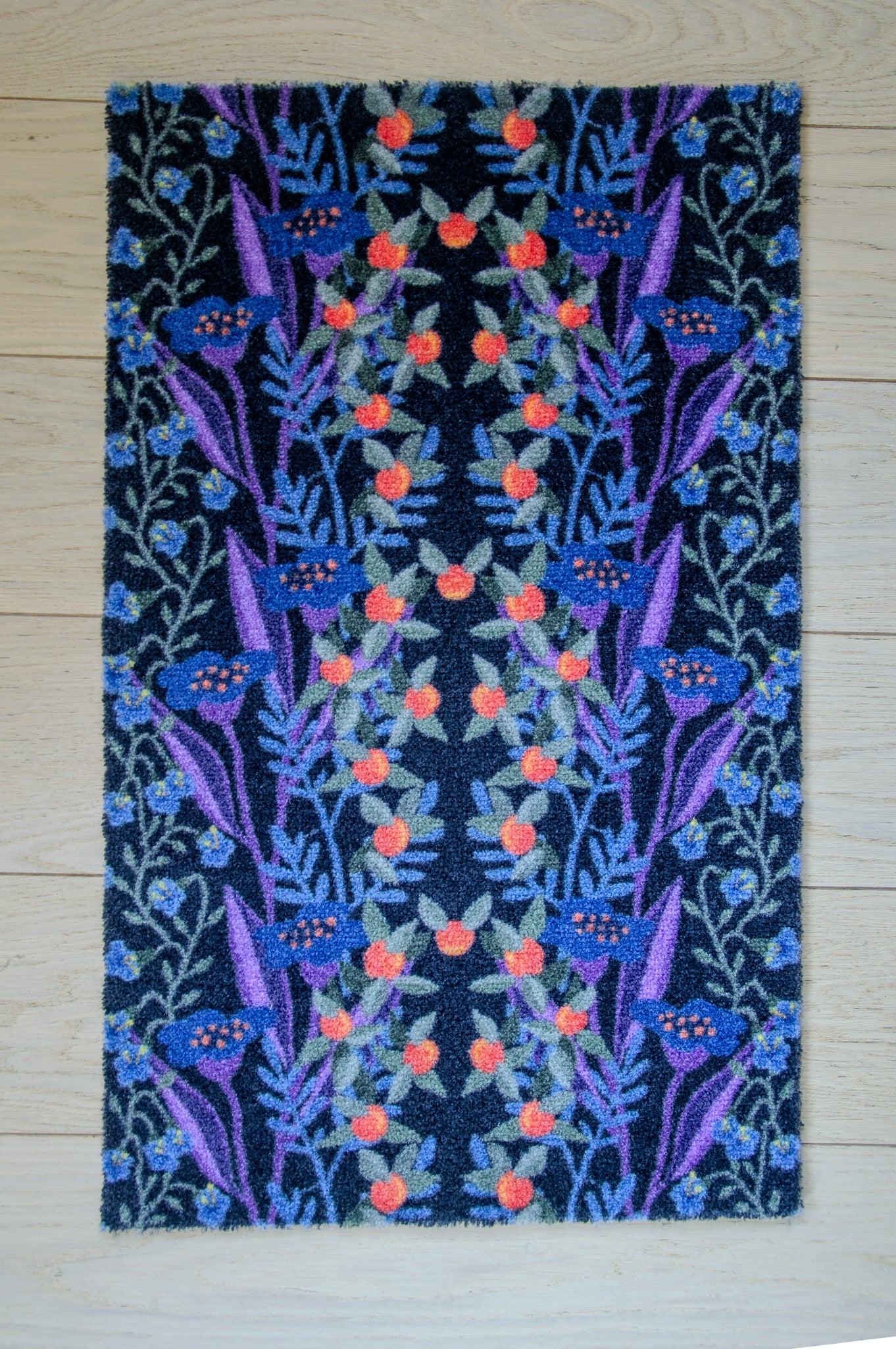 Zachte, waterabsorberende badmat van Studio LilaLine met een gestileerde bessenprint in zwart, blauw en rood – het ontwerp toont organische vormen die speels over de mat verspreid liggen, met een grafische uitstraling en diepe kleuren. De mat voelt comfortabel aan onder de voeten en brengt een stoer, stijlvol accent in de badkamer.