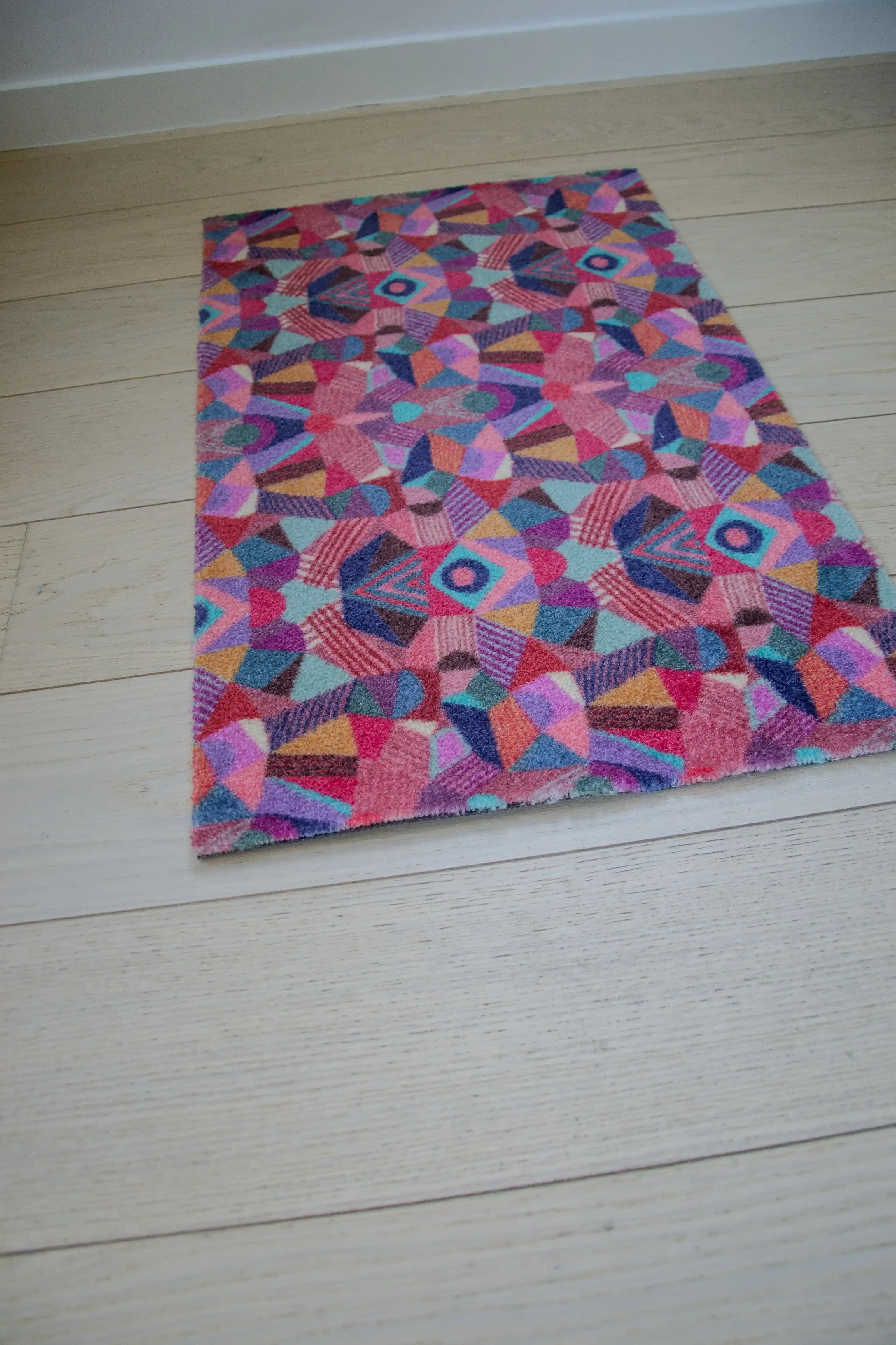 Zachte en goed absorberende badmat van Studio LilaLine met een kleurrijk patroon in roze, rood, groen en blauw – het ontwerp lijkt op de symmetrische patronen van een caleidoscoop, met speelse vormen die in lagen over elkaar draaien. De levendige kleuren maken deze mat een echte blikvanger in de badkamer. Heerlijk zacht voor je voeten na het douchen of badderen.