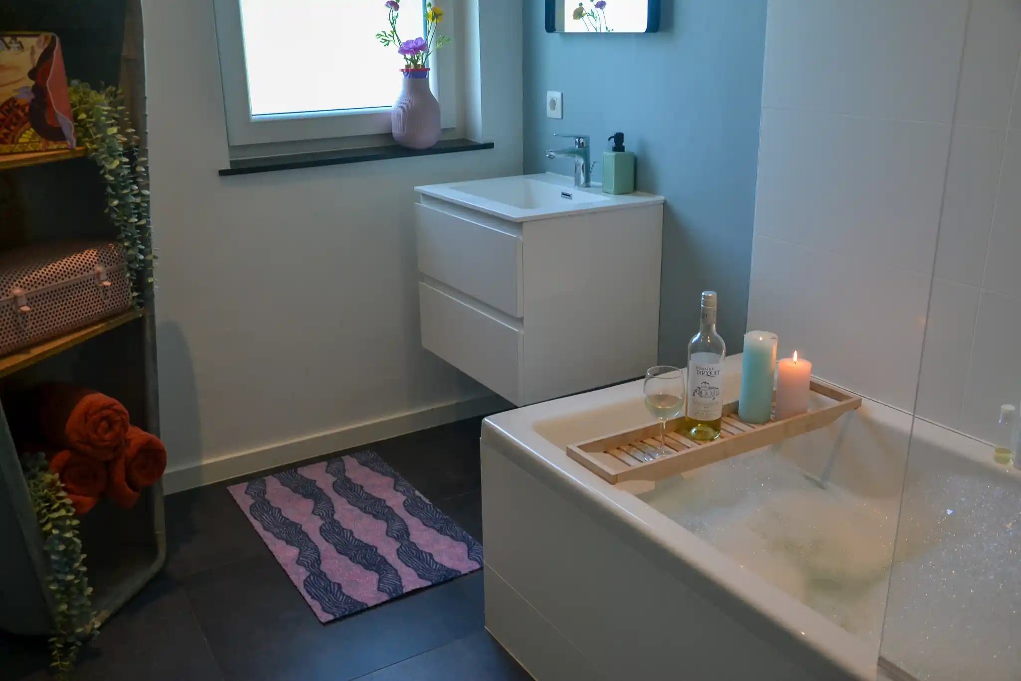 Zachte en goed absorberende badmat van Studio LilaLine met een golvend patroon in paarstinten – het ontwerp bestaat uit ritmische lijnen in ton-sur-ton die zacht in elkaar overlopen, alsof je kijkt naar rustige waterstromen in de schemering. De mat voelt heerlijk zacht aan onder de voeten en brengt een kalme, stijlvolle sfeer in de badkamer.
