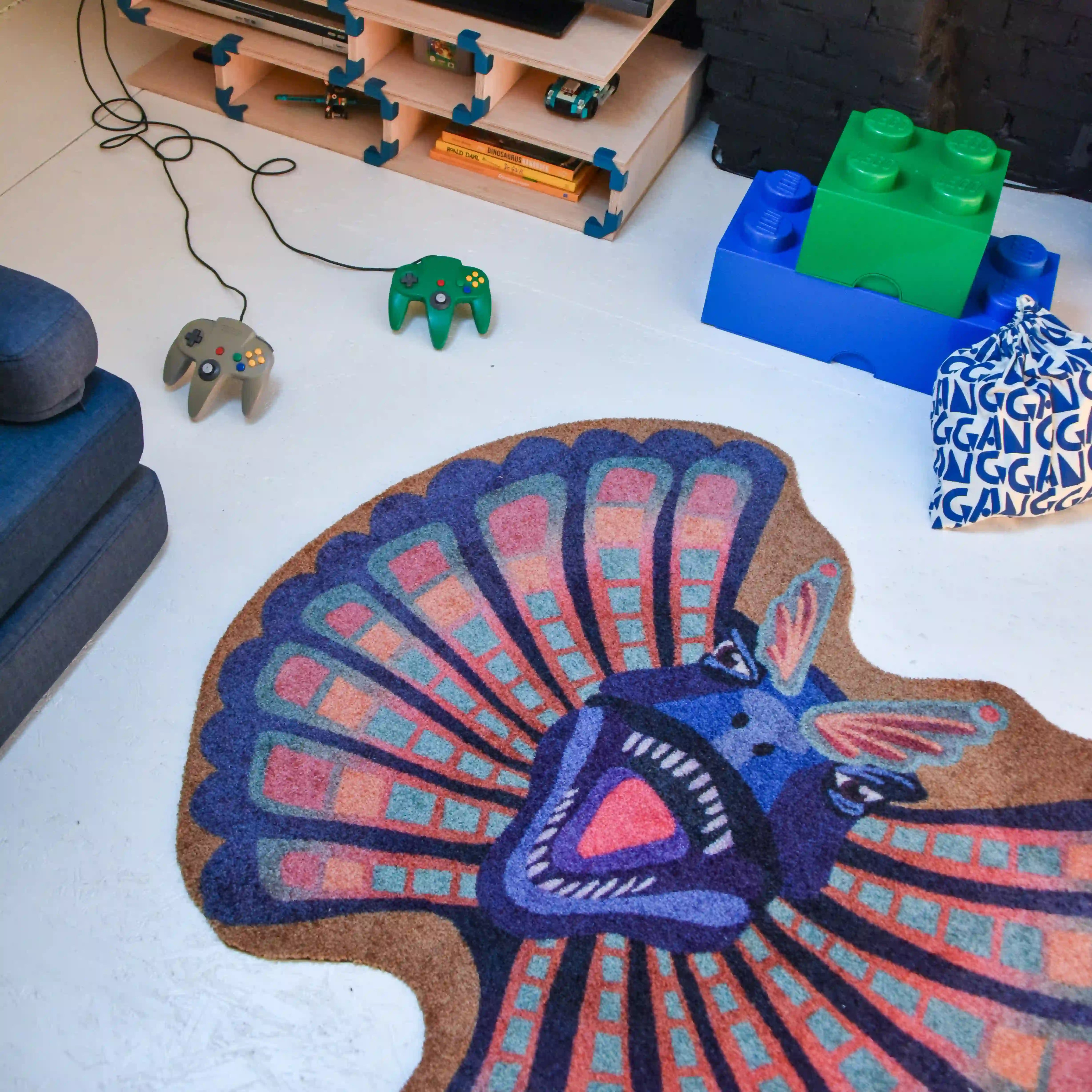 Alt-tekst:
Zacht uitgesneden dierenkleed in de vorm van een dilophosaurus-hoofd van Studio LilaLine – het kleed beeldt de dinosaurus af met zijn opvallende kraag wijd uitgespreid, in tinten van blauw en warm oker. De kraag heeft puntige vormen en een waaierachtige uitstraling, terwijl het gezicht expressief en stoer is. Een fantasierijke en zachte speelplek voor dino-liefhebbers in de kinderkamer.