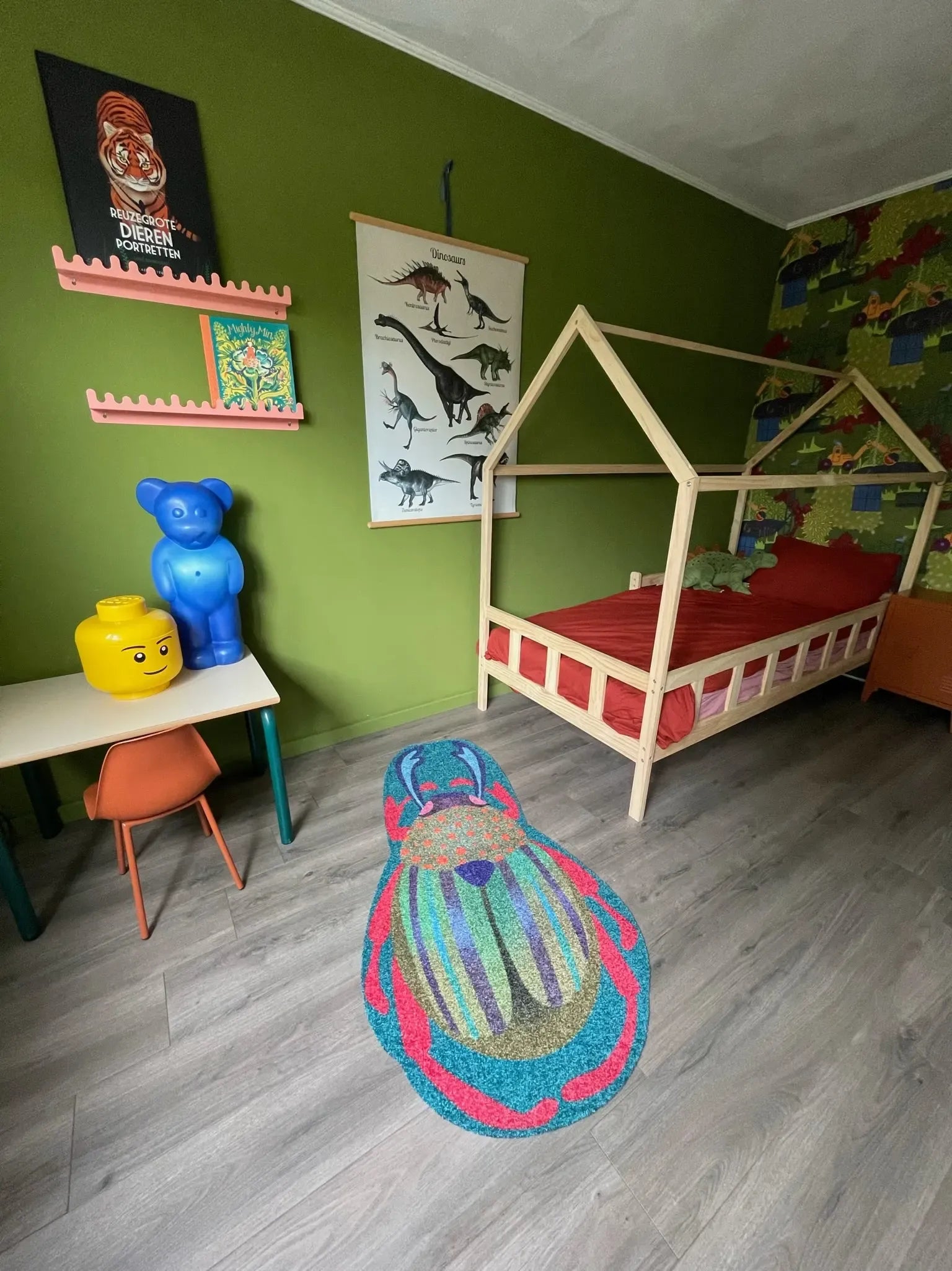 Zacht uitgesneden dierenkleed in de vorm van een kever, van bovenaf gezien, van Studio LilaLine – dit kleed toont een fantasierijke kever in felle groentinten met rode accenten. Het lijf is ovaal en glanzend, zonder strepen, en heeft een glad, vloeiend oppervlak. De pootjes en voelsprieten steken subtiel uit. Het kleed is heerlijk zacht en nodigt uit tot spelen of zitten in een kleurrijke kinderkamer.