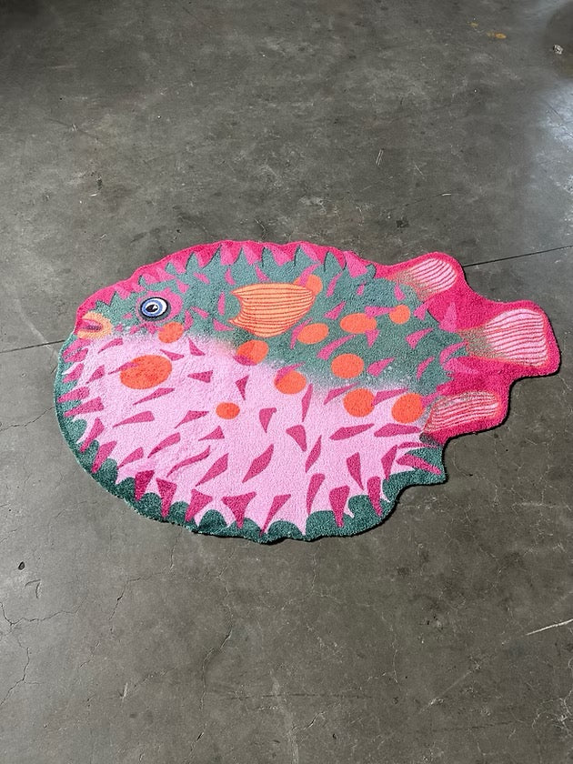 Zacht uitgesneden dierenkleed in de vorm van een kogelvis van Studio LilaLine – het kleed toont een ronde vis met grappige stekelvormen, uitgevoerd in frisse roze en groentinten. De vis heeft een vriendelijke uitstraling met een bolle buik en sprekende ogen. Het oppervlak is zacht en comfortabel, perfect om op te spelen of lekker te zitten in een speelhoek of kinderkamer.