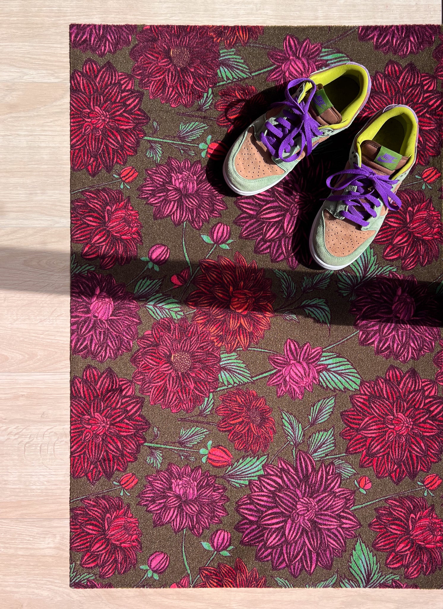 Droogloopmat met roze dahlia's op een zachte mosgroene achtergrond. Een frisse, elegante lenteprint die rust en vrolijkheid combineert.