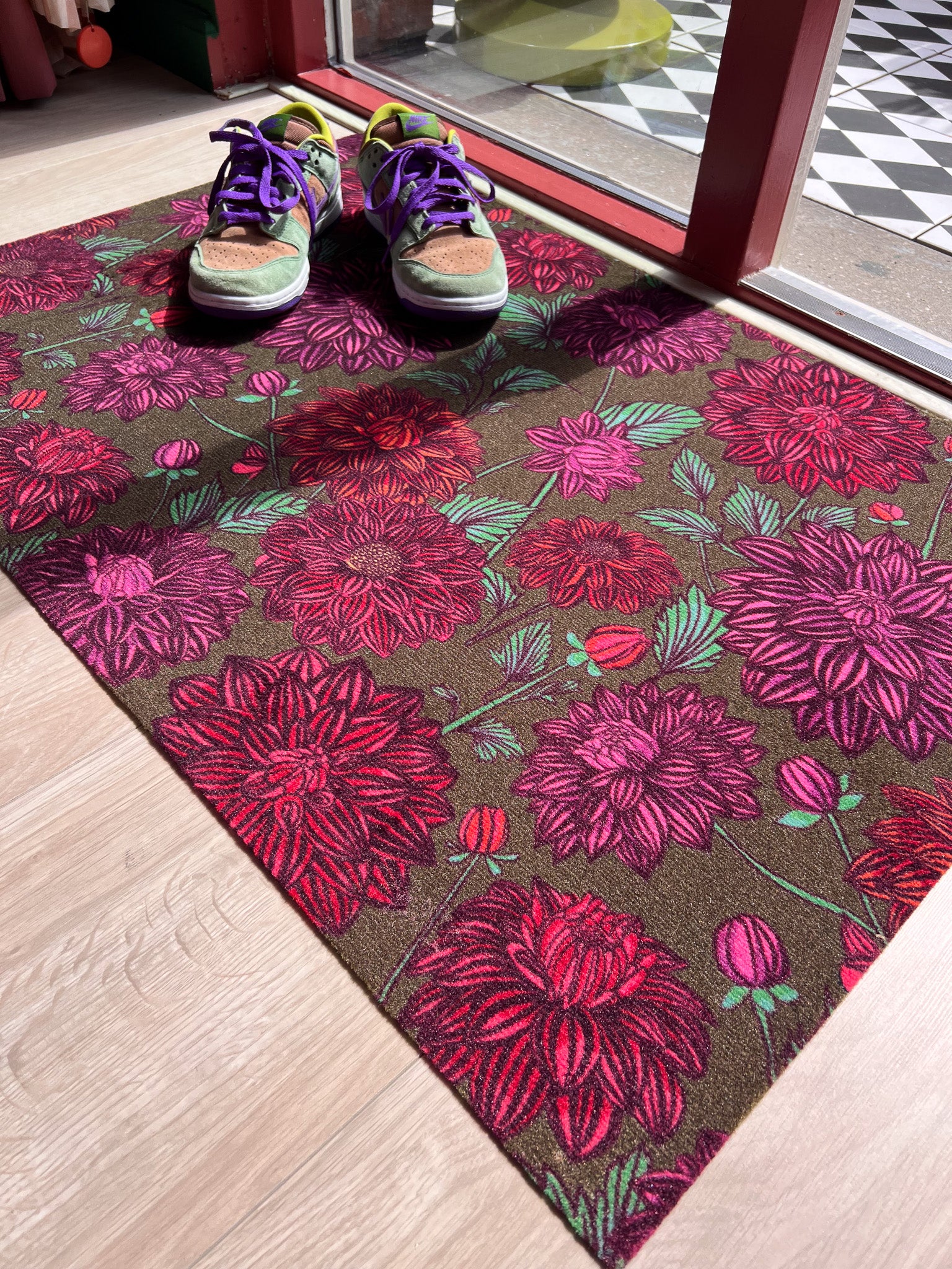 Droogloopmat met roze dahlia's op een zachte mosgroene achtergrond. Een frisse, elegante lenteprint die rust en vrolijkheid combineert.