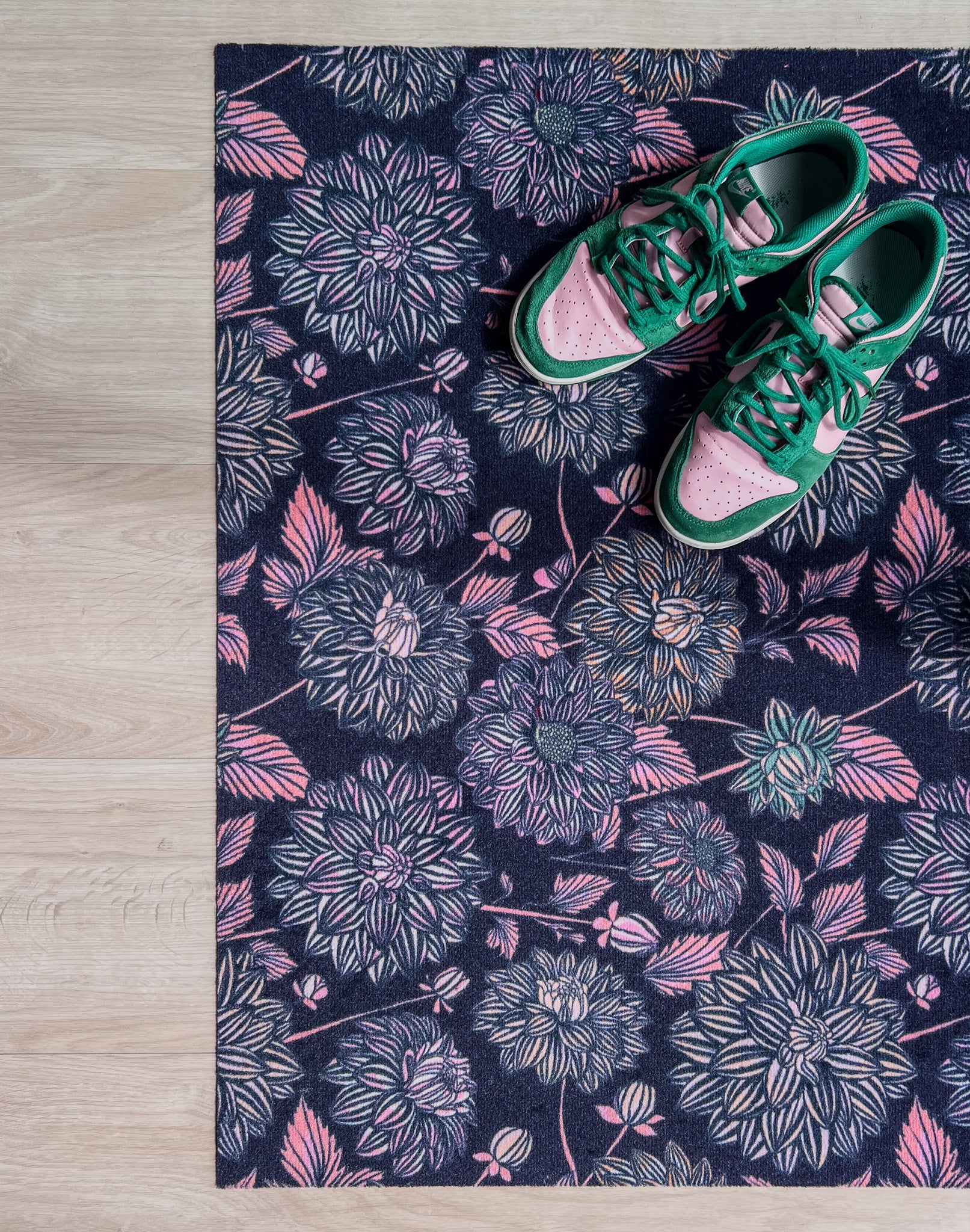 Droogloopmat met dahlia’s in roze en blauwtinten op een diep donkerblauwe basis. Een gelaagde, winterse bloemenprint met een dromerige uitstraling.