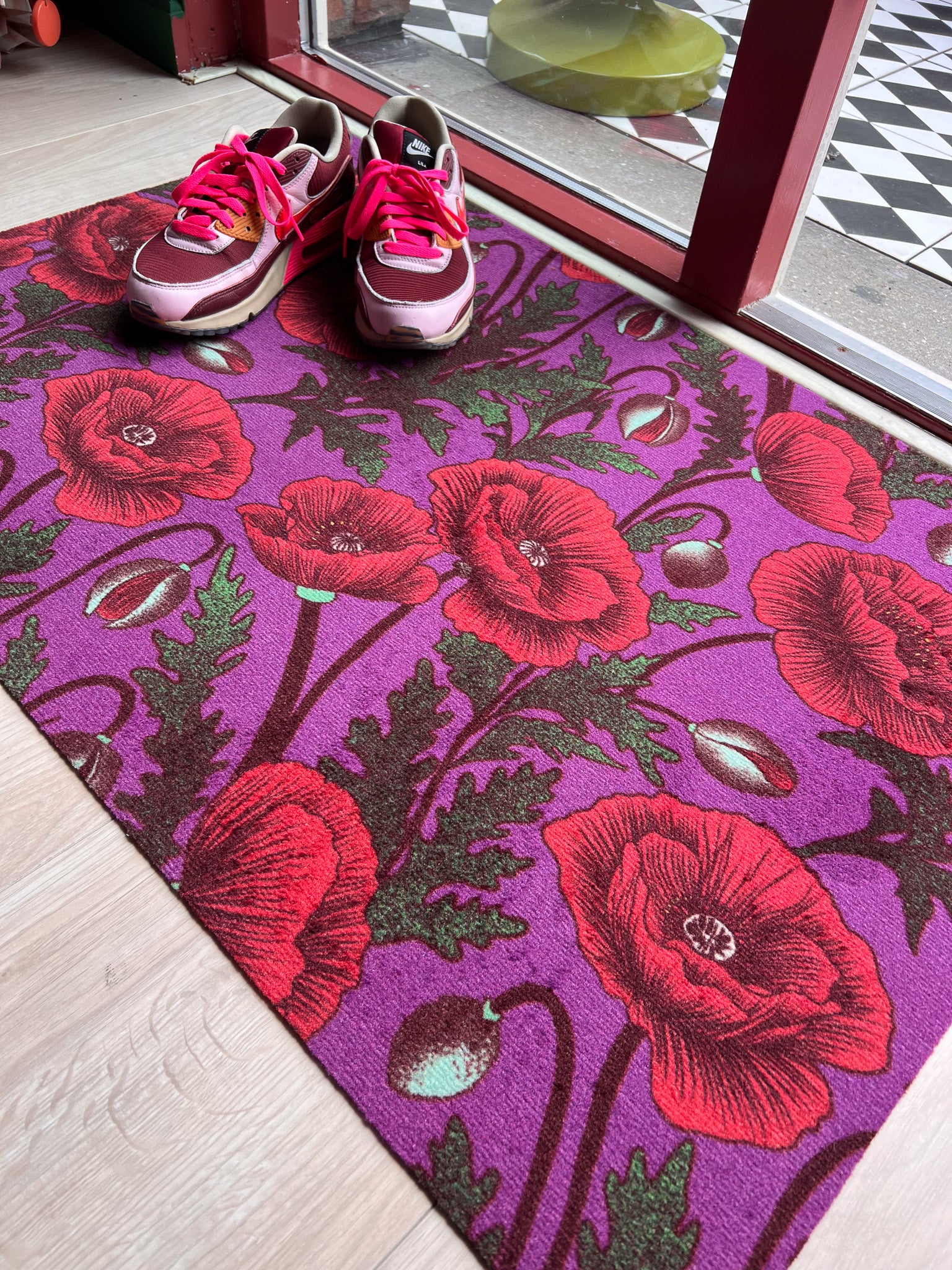Droogloopmat met opvallende knalrode klaprozen op een diepe paarse ondergrond. Een krachtige, zomerse print vol contrast en energie.
