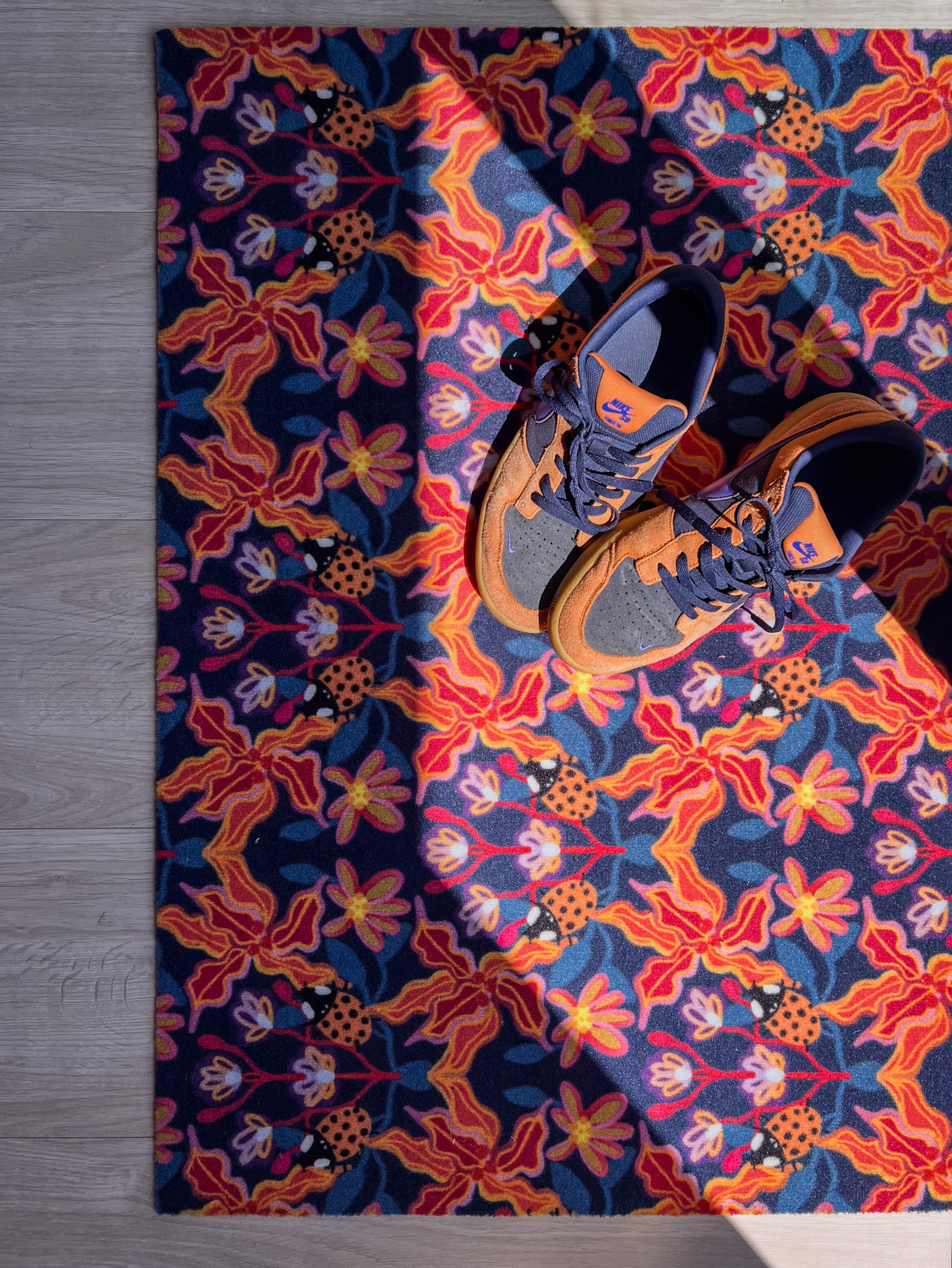 Droogloopmat en deurmat van Studio LilaLine met een vrolijke print geïnspireerd op een lieveheersbeestje, in opvallende tinten oranje en blauw – het ontwerp combineert ronde vormen met een speels patroon dat direct opvalt in je hal. De mat is slijtvast, neemt goed vocht op en brengt een kleurrijke, opgewekte sfeer in huis.