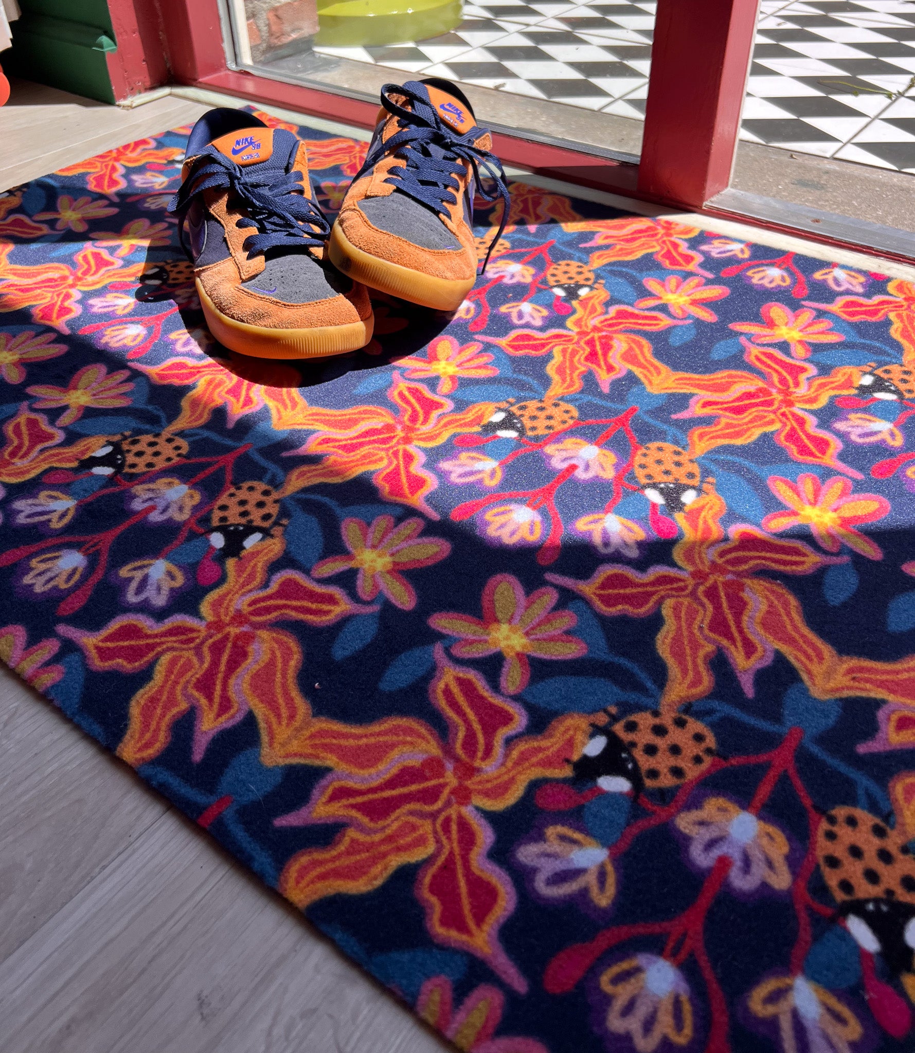 Droogloopmat en deurmat van Studio LilaLine met een vrolijke print geïnspireerd op een lieveheersbeestje, in opvallende tinten oranje en blauw – het ontwerp combineert ronde vormen met een speels patroon dat direct opvalt in je hal. De mat is slijtvast, neemt goed vocht op en brengt een kleurrijke, opgewekte sfeer in huis.