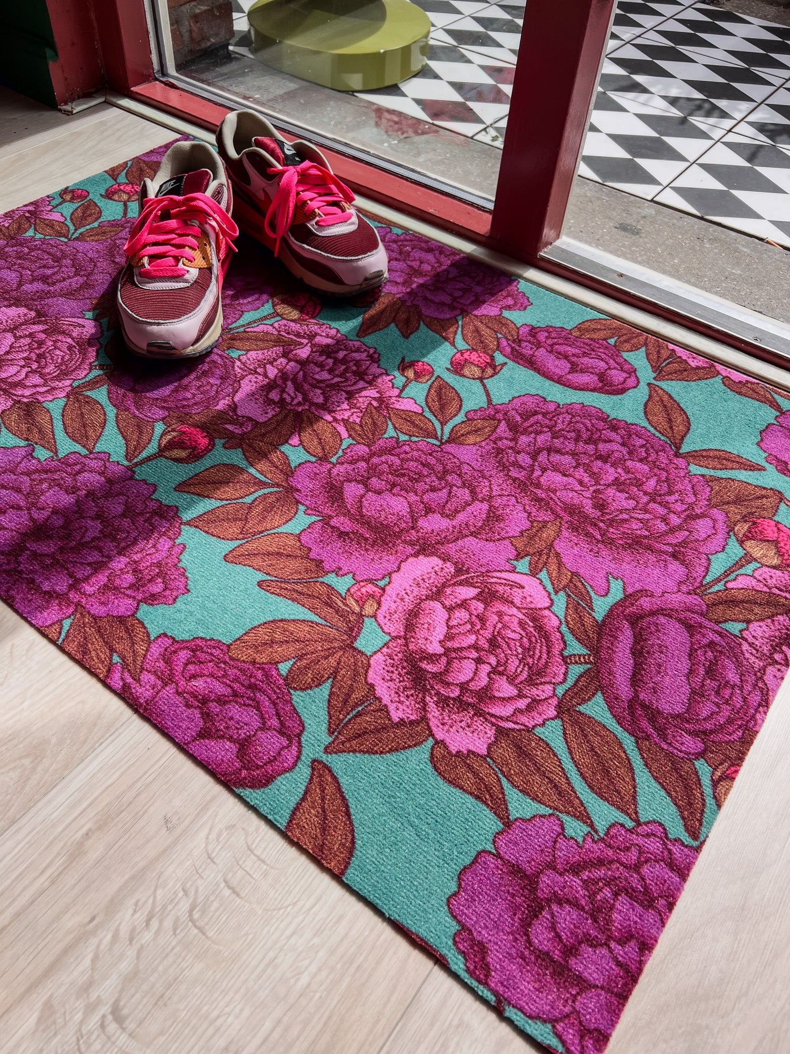 Droogloopmat met roze pioenrozen op een frisse petrolgroene achtergrond. Een zachte, lenteachtige bloemenprint die je hal laat opbloeien.