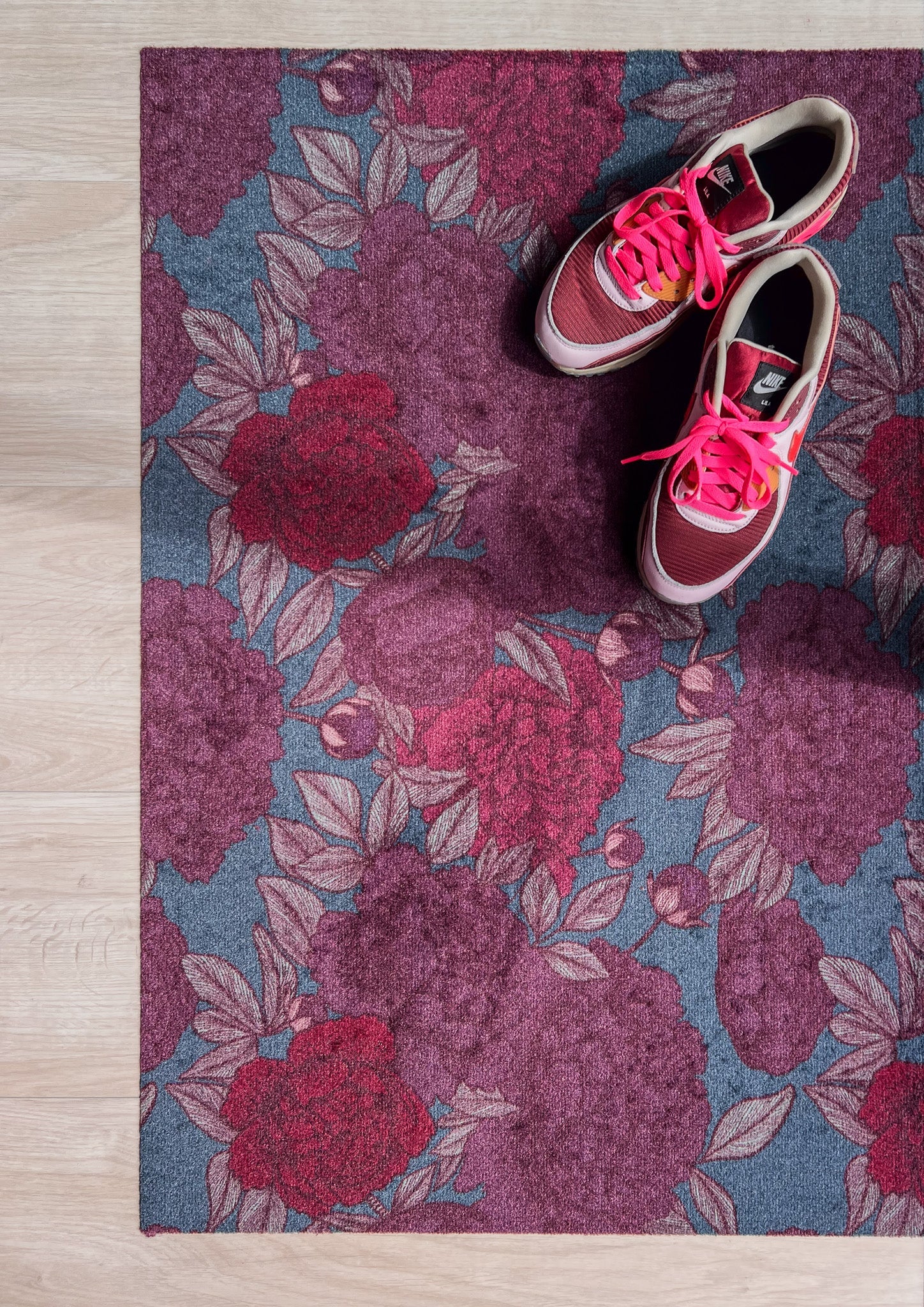 Droogloopmat met oudroze en rode pioenrozen op een vergrijsd blauwe ondergrond. Een elegante, winterse bloemenprint die rust en stijl brengt.