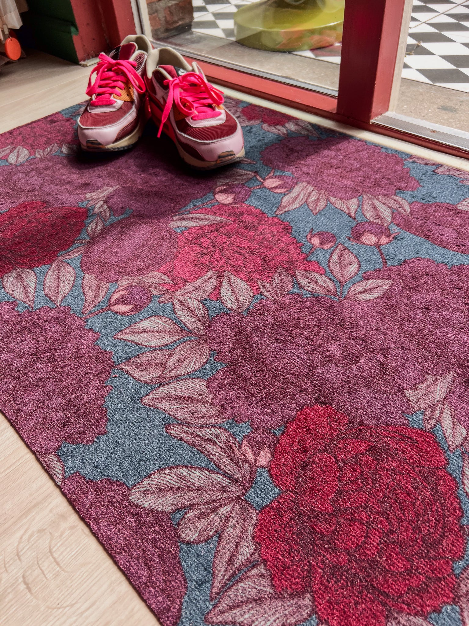 Droogloopmat met oudroze en rode pioenrozen op een vergrijsd blauwe ondergrond. Een elegante, winterse bloemenprint die rust en stijl brengt.