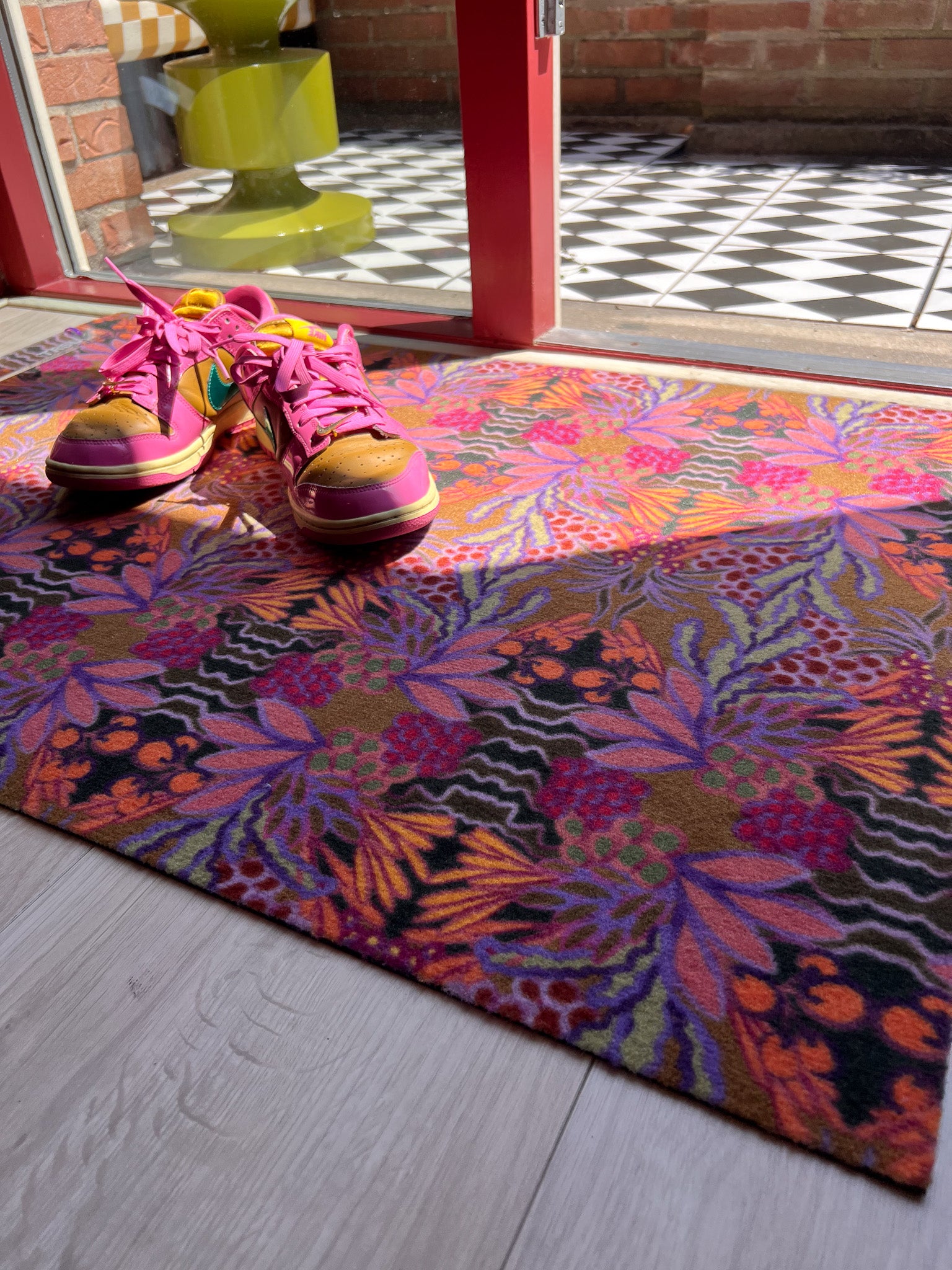 Droogloopmat en deurmat van Studio LilaLine met een uitbundige tropische bloemenprint in warme oranje- en paarstinten – het ontwerp straalt zon, vrolijkheid en zomerse energie uit. De mat is slijtvast, neemt vocht goed op en fleurt elke entree op met kleur en karakter. Perfect voor binnen én beschutte buitenruimtes.