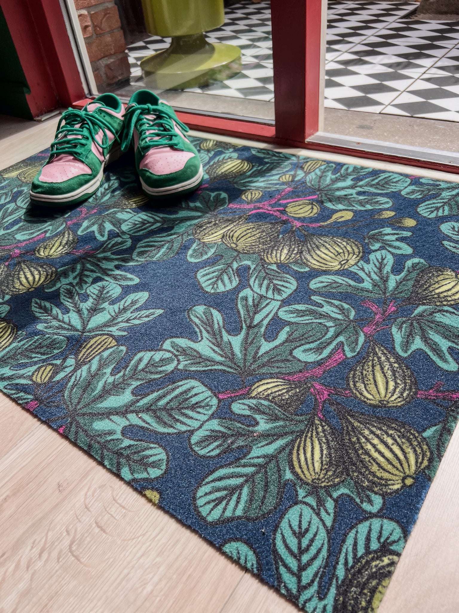 Droogloopmat met grafische vijgenbladeren in felgroen, petrol en zacht mosgroen. Een frisse, winterse mat met een stoer botanisch karakter.
