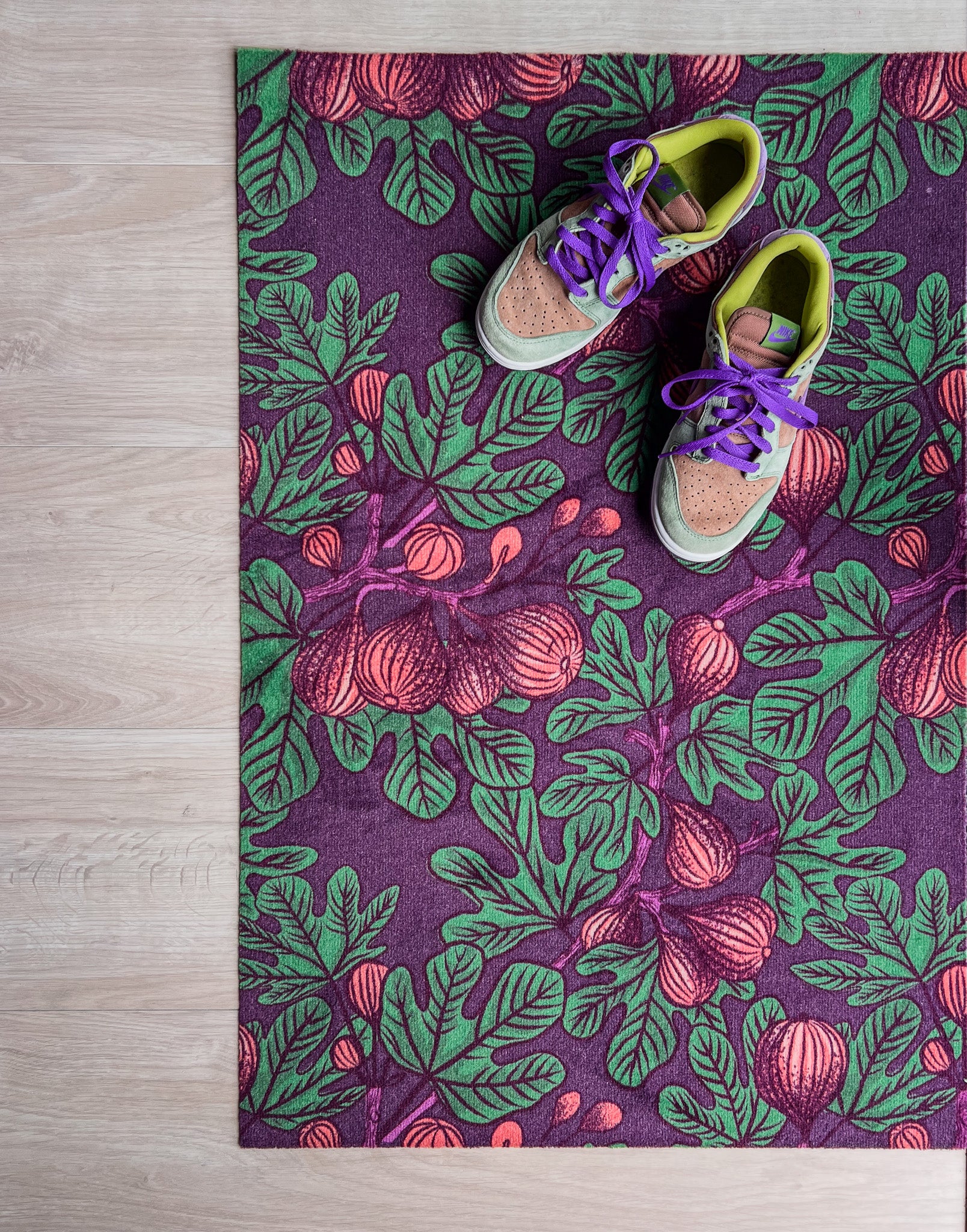 Droogloopmat met vijgenbladmotief in mauve met accenten van donkerpaars en donkergroen. Een diepe, zomerse print met mediterrane warmte.