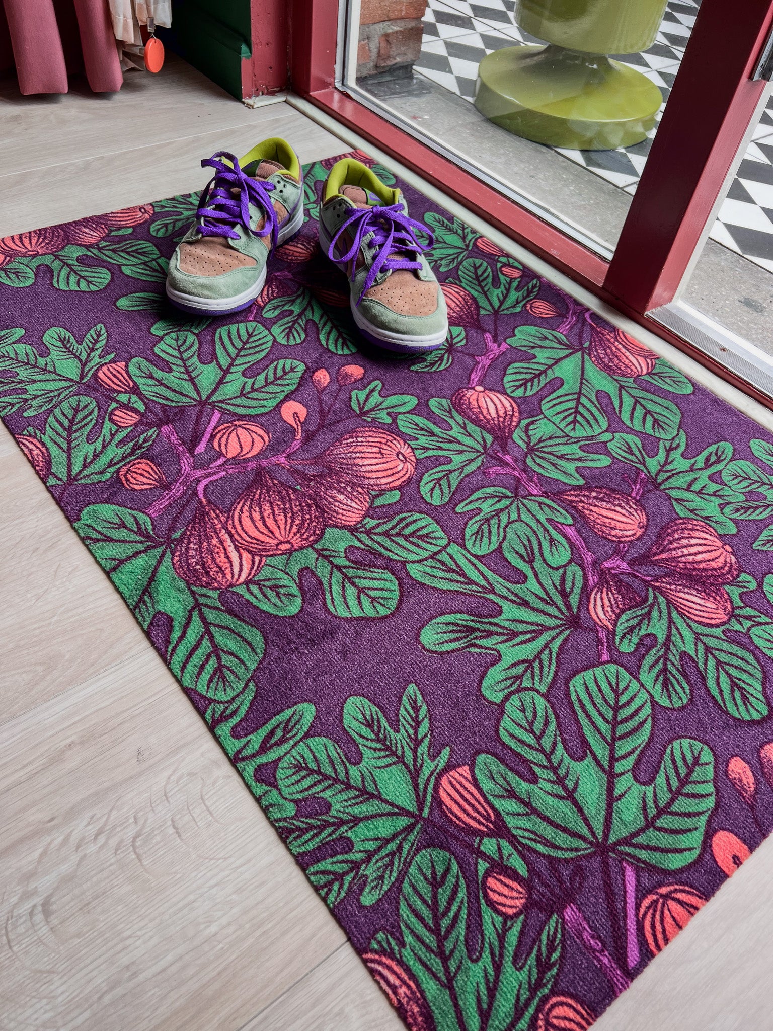 Droogloopmat met vijgenbladmotief in mauve met accenten van donkerpaars en donkergroen. Een diepe, zomerse print met mediterrane warmte.