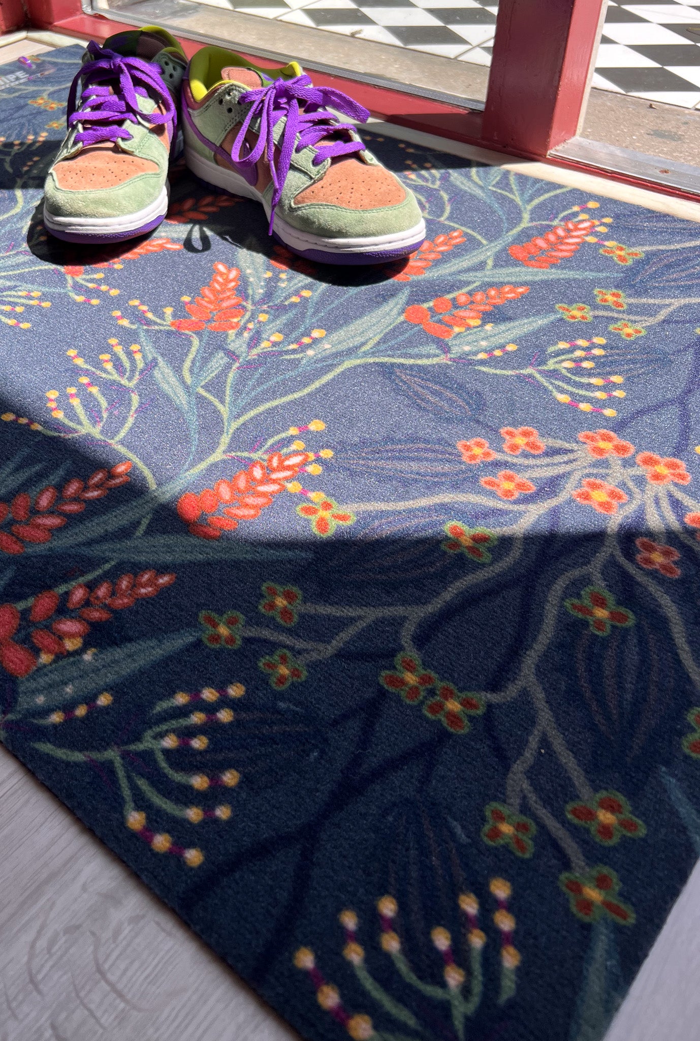 Op maat gemaakte droogloopmat van Studio LilaLine met een sierlijk patroon geïnspireerd op bloeiende blauwe regen – uitgevoerd in diepe petroltinten met verfijnde bloemvormen die als een waterval over de mat lijken te hangen. De print heeft een rustige, elegante uitstraling. De mat is slijtvast, vochtopnemend en perfect voor een stijlvolle entree.