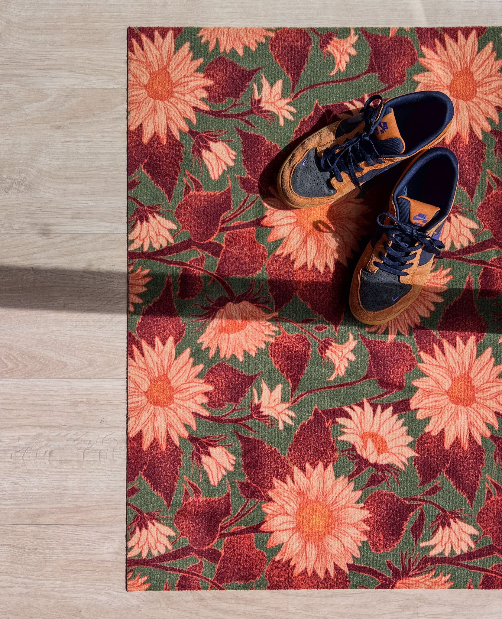 Droogloopmat met zachte perzikkleurige zonnebloemen op een donkergroene achtergrond. De print straalt herfstwarmte en natuurlijke charme uit.