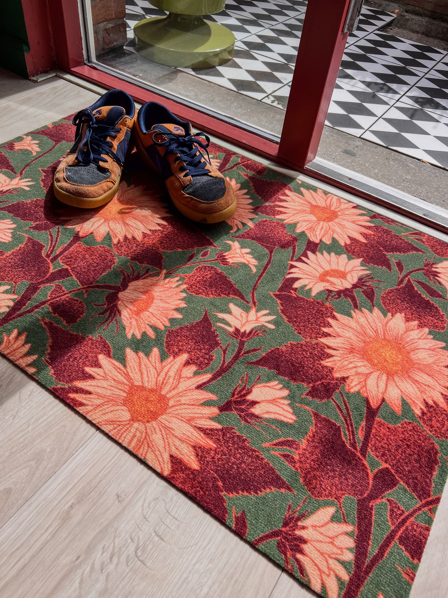 Droogloopmat met zachte perzikkleurige zonnebloemen op een donkergroene achtergrond. De print straalt herfstwarmte en natuurlijke charme uit.