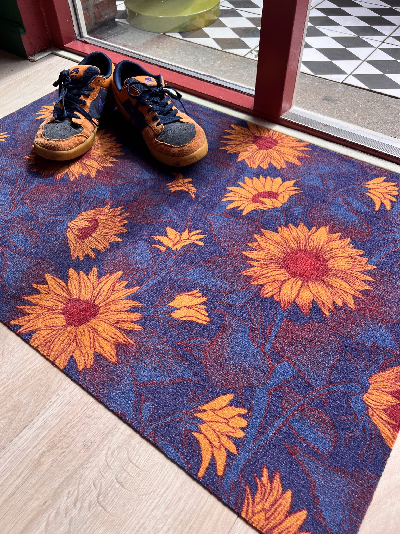 Droogloopmat met okergele zonnebloemen op een diepe donkerblauwe ondergrond. Een krachtige, winterse bloemenprint die sfeer en warmte brengt bij binnenkomst.