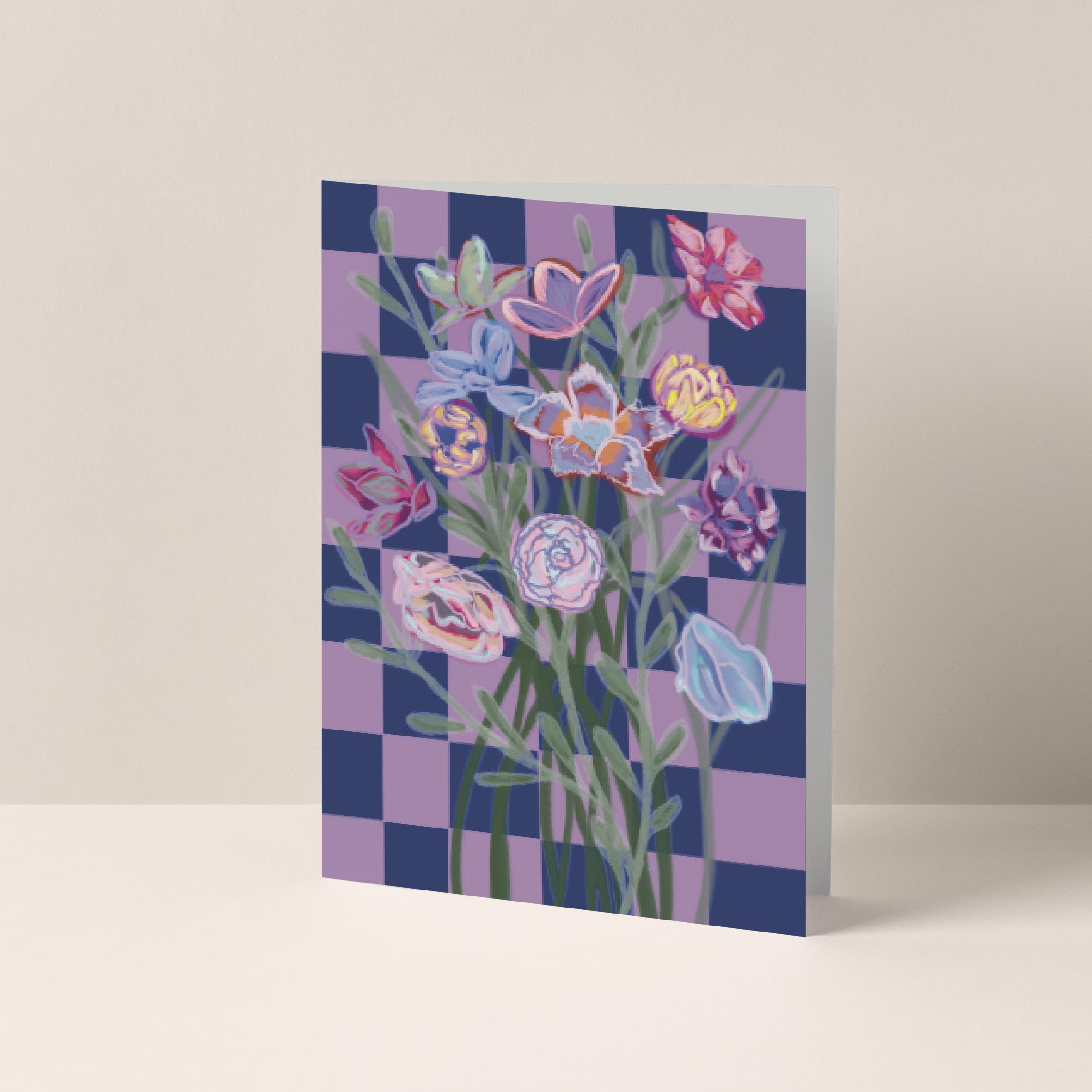 Dubbelgevouwen A6-kaart van Studio LilaLine met op de voorkant een speels ontwerp – een blauw-roze geblokt patroon als achtergrond met in het midden een pastel boeket bloemen. De bloemen zijn zacht en dromerig, met tinten die mooi afsteken tegen het grafische dambord. Het contrast tussen het patroon en het boeket geeft de kaart een frisse, vrolijke uitstraling. De binnenkant is blanco en biedt ruimte voor een persoonlijke boodschap.