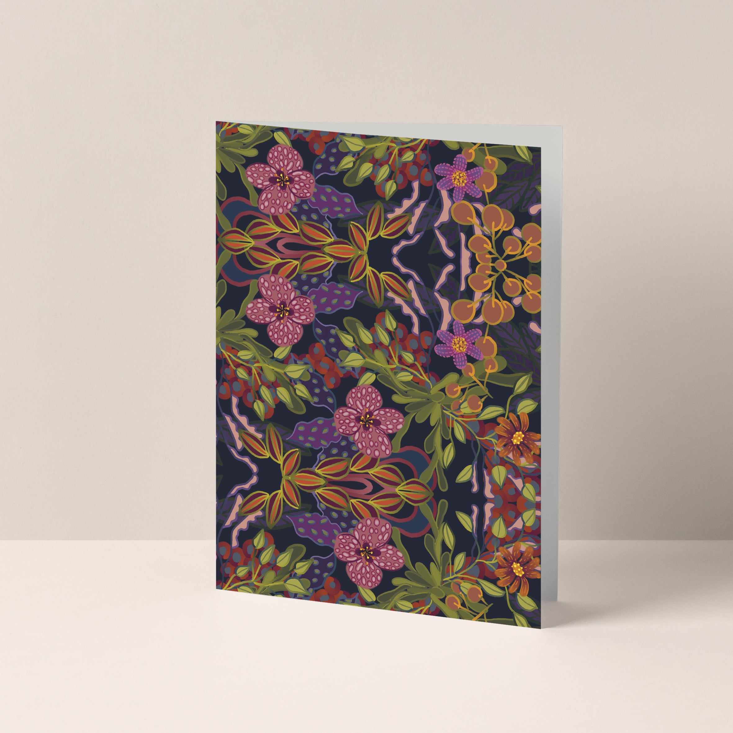 Dubbelgevouwen A6-kaart van Studio LilaLine met op de voorkant een betoverende bloemenprint in paars, roze en groen – het ontwerp toont bloemen die lijken te bloeien in het maanlicht, met diepe kleuren en sierlijke vormen. De sfeer is mysterieus en poëtisch, alsof de bloemen tot leven komen in de nacht. De binnenkant is blanco en geschikt voor een persoonlijke boodschap.