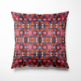 Kussen voor binnen en buiten met een kleurrijke bloemenprint in warme tinten rood, roze en oranje, aangevuld met accenten van kobaltblauw en zonnig geel. De print is rijk en gedetailleerd, als een liefdesexplosie in bloei. Het patroon is symmetrisch opgebouwd en voelt feestelijk, speels en toch gebalanceerd. Gemaakt van stevige stof die geschikt is voor zowel binnen op de bank als buiten op je loungeset.