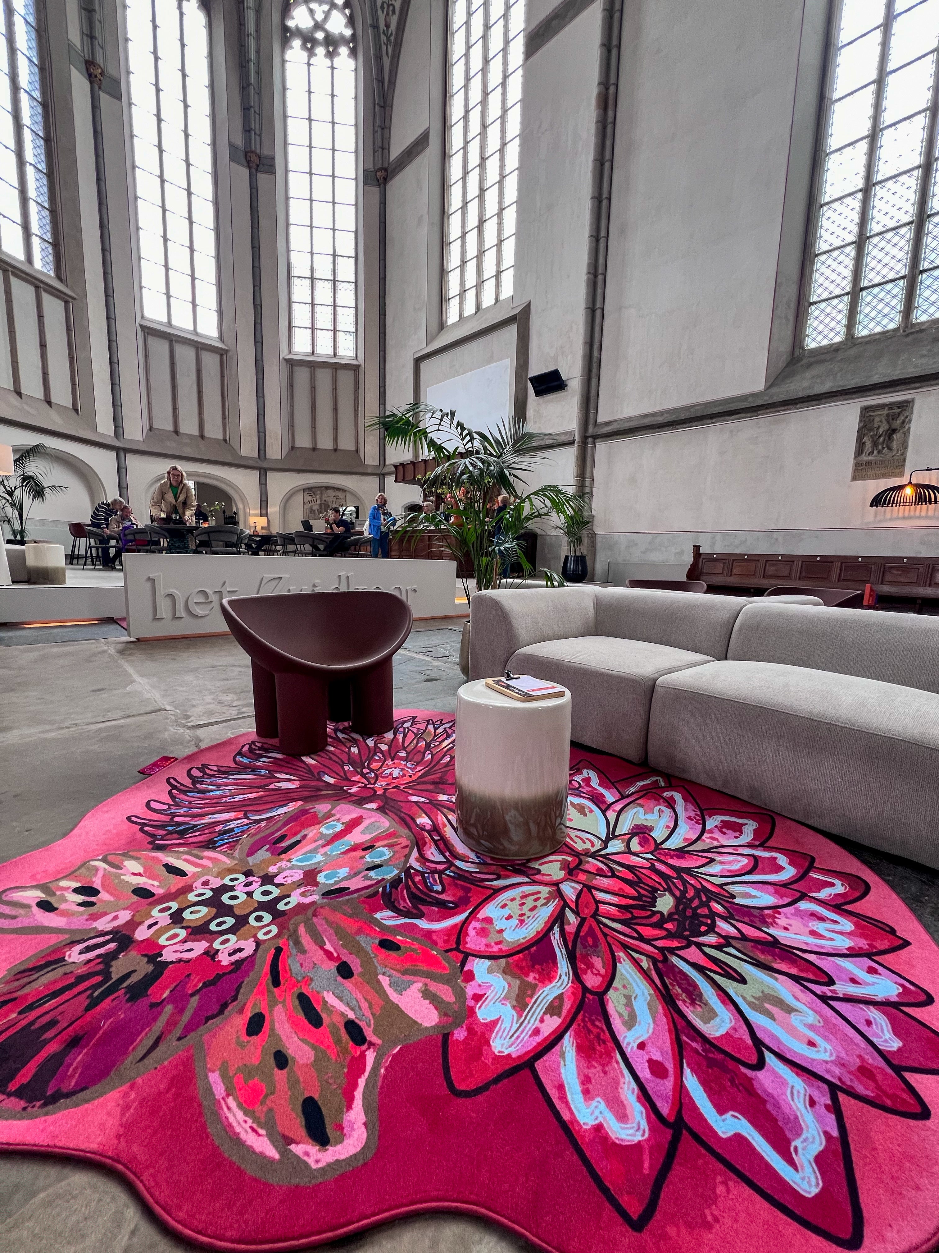 Luxe vloerkleed Dahlia Roze van Studio LilaLine met drie grote dahlia-bloemen in de hoofdrol – de bloemen zijn weelderig en gelaagd, opgebouwd uit rijke roze en rode tinten met hier en daar een warme oranje gloed. De vormen zijn rond en zacht, alsof de bloemblaadjes zich langzaam ontvouwen. Het kleed voelt zacht en warm aan, en straalt een romantische, uitnodigende sfeer uit in de ruimte.
