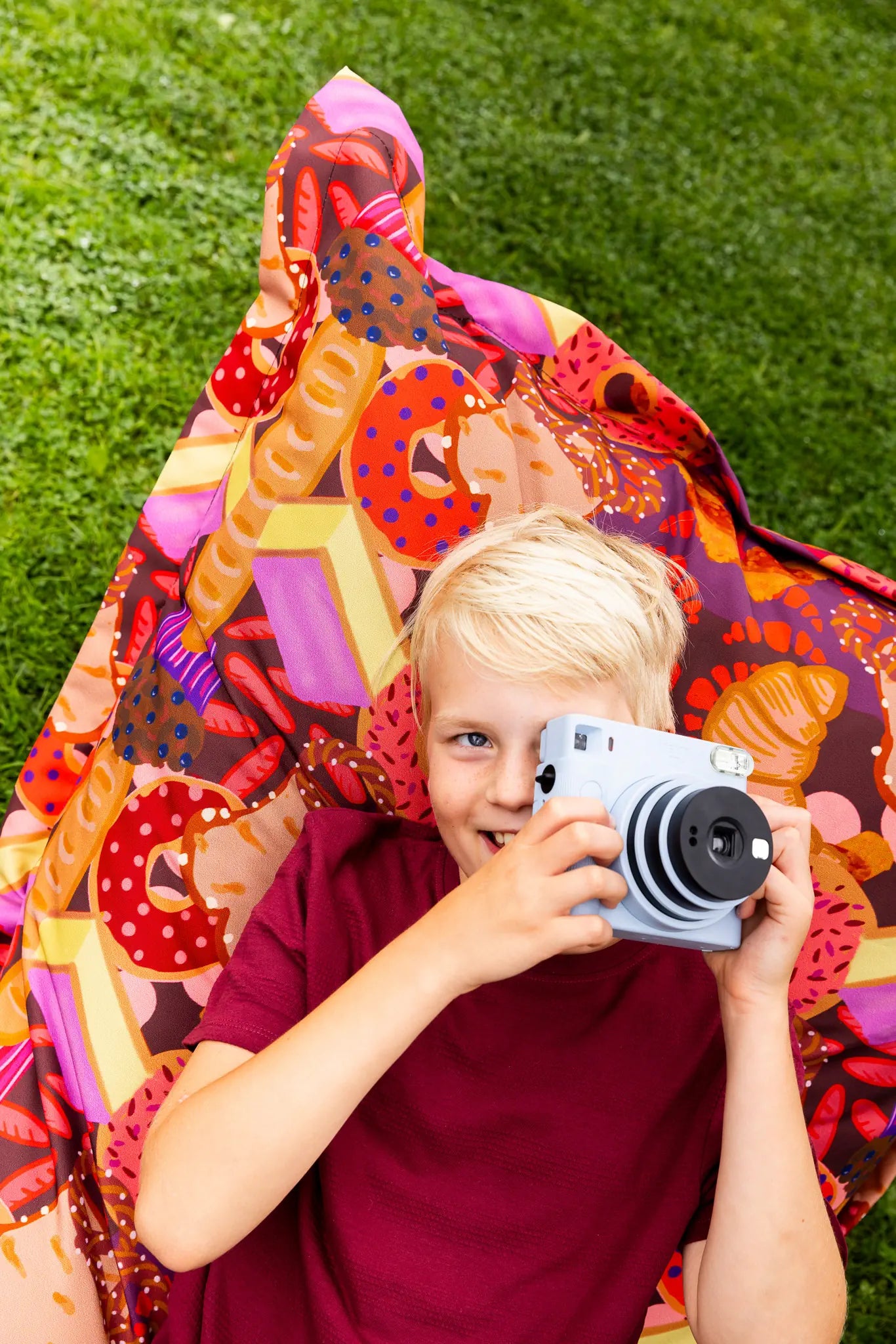 Zachte en speelse zitzak van Studio LilaLine met een print vol zoete lekkernijen in roze en petrol – het ontwerp toont koekjes, taartjes en andere vrolijke vormen in een dromerige, feestelijke stijl. De zitzak is gemaakt van stevige buitenstof en daardoor geschikt voor binnen en buiten. Perfect om in te relaxen met een glimlach, of gewoon even heerlijk te dagdromen.