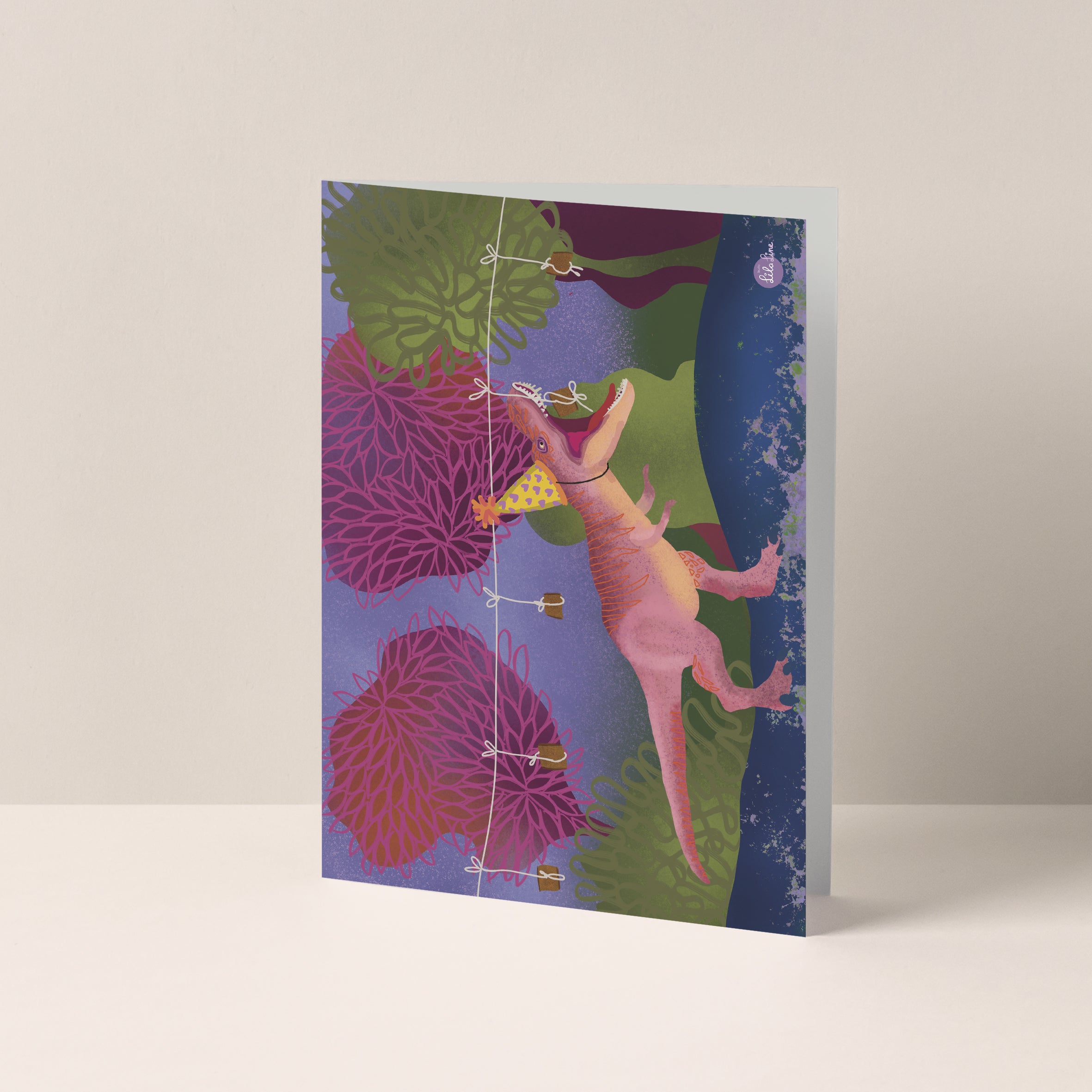 Dubbelgevouwen A6-kaart van Studio LilaLine met op de voorkant een vrolijke illustratie van een T-Rex die koekhapt – de dino heeft zijn bek wijd open en hangt met zijn tanden naar een slinger met koekjes. De stijl is speels en kleurrijk, met grappige details die kinderen aanspreken. De binnenkant van de kaart is blanco en biedt ruimte voor een persoonlijke boodschap.