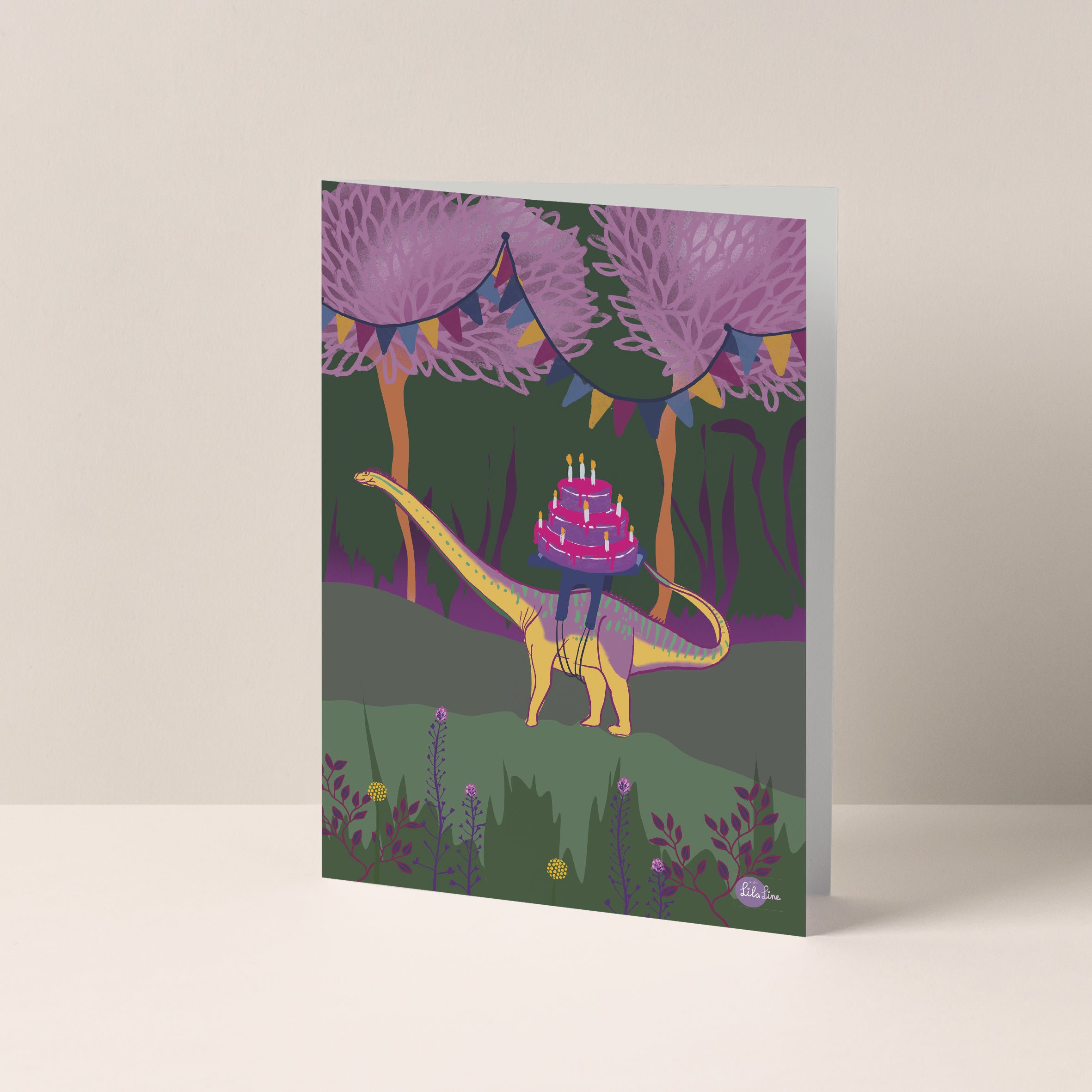 Dubbelgevouwen A6-kaart van Studio LilaLine met op de voorkant een vrolijke dino met een lange nek – waarschijnlijk een brachiosaurus of apatosaurus – die een grote verjaardagstaart op zijn rug draagt. De taart is rijk versierd met kaarsjes en vrolijke kleuren. De illustratie straalt feestelijkheid en zachtheid uit. De binnenkant van de kaart is blanco en klaar voor een persoonlijke boodschap.