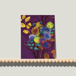 Enkele A6-kaart van Studio LilaLine met een expressieve dahlia-print op de voorkant – de bloem is vol en rond, opgebouwd uit lagen bloemblaadjes in paars, geel en blauw. De kleuren vloeien speels in elkaar over en geven de bloem een levendige en energieke uitstraling. De compositie is symmetrisch en krachtig. Op de achterkant is ruimte voor een persoonlijke boodschap.