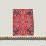 Enkele A6-kaart van Studio LilaLine met een sierlijke spiegelbloemenprint op de voorkant – het ontwerp toont symmetrische bloemvormen in warme roze tinten, met subtiele schakeringen die doen denken aan bloemblaadjes in volle bloei. De compositie is zacht en evenwichtig, met een elegante uitstraling. De achterkant is blanco en geschikt voor een persoonlijke boodschap.