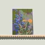 Enkele A6-kaart van Studio LilaLine met een gestileerde paardenbloemprint op de voorkant – het ontwerp toont een ronde, pluizige paardenbloem in tinten van groen, blauw en zacht geel. De fijne lijnen stralen naar buiten als een zonnetje vol zaden die elk moment kunnen wegwaaien. De compositie is licht en speels, met een frisse en natuurlijke uitstraling. De achterkant biedt ruimte voor een handgeschreven boodschap.