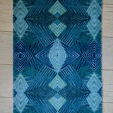 Zachte, waterabsorberende badmat van Studio LilaLine met een grafisch diamantpatroon in tinten petrol, blauw en groen – het ontwerp bestaat uit ritmische lijnen en geometrische vormen die samen een kalme, frisse uitstraling geven. De mat voelt aangenaam onder blote voeten en brengt kleur en stijl in de badkamer.