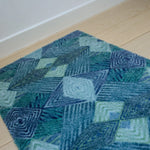 Zachte, waterabsorberende badmat van Studio LilaLine met een grafisch diamantpatroon in tinten petrol, blauw en groen – het ontwerp bestaat uit ritmische lijnen en geometrische vormen die samen een kalme, frisse uitstraling geven. De mat voelt aangenaam onder blote voeten en brengt kleur en stijl in de badkamer.