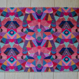 Zachte en goed absorberende badmat van Studio LilaLine met een kleurrijk patroon in roze, rood, groen en blauw – het ontwerp lijkt op de symmetrische patronen van een caleidoscoop, met speelse vormen die in lagen over elkaar draaien. De levendige kleuren maken deze mat een echte blikvanger in de badkamer. Heerlijk zacht voor je voeten na het douchen of badderen.