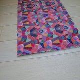 Zachte en goed absorberende badmat van Studio LilaLine met een kleurrijk patroon in roze, rood, groen en blauw – het ontwerp lijkt op de symmetrische patronen van een caleidoscoop, met speelse vormen die in lagen over elkaar draaien. De levendige kleuren maken deze mat een echte blikvanger in de badkamer. Heerlijk zacht voor je voeten na het douchen of badderen.
