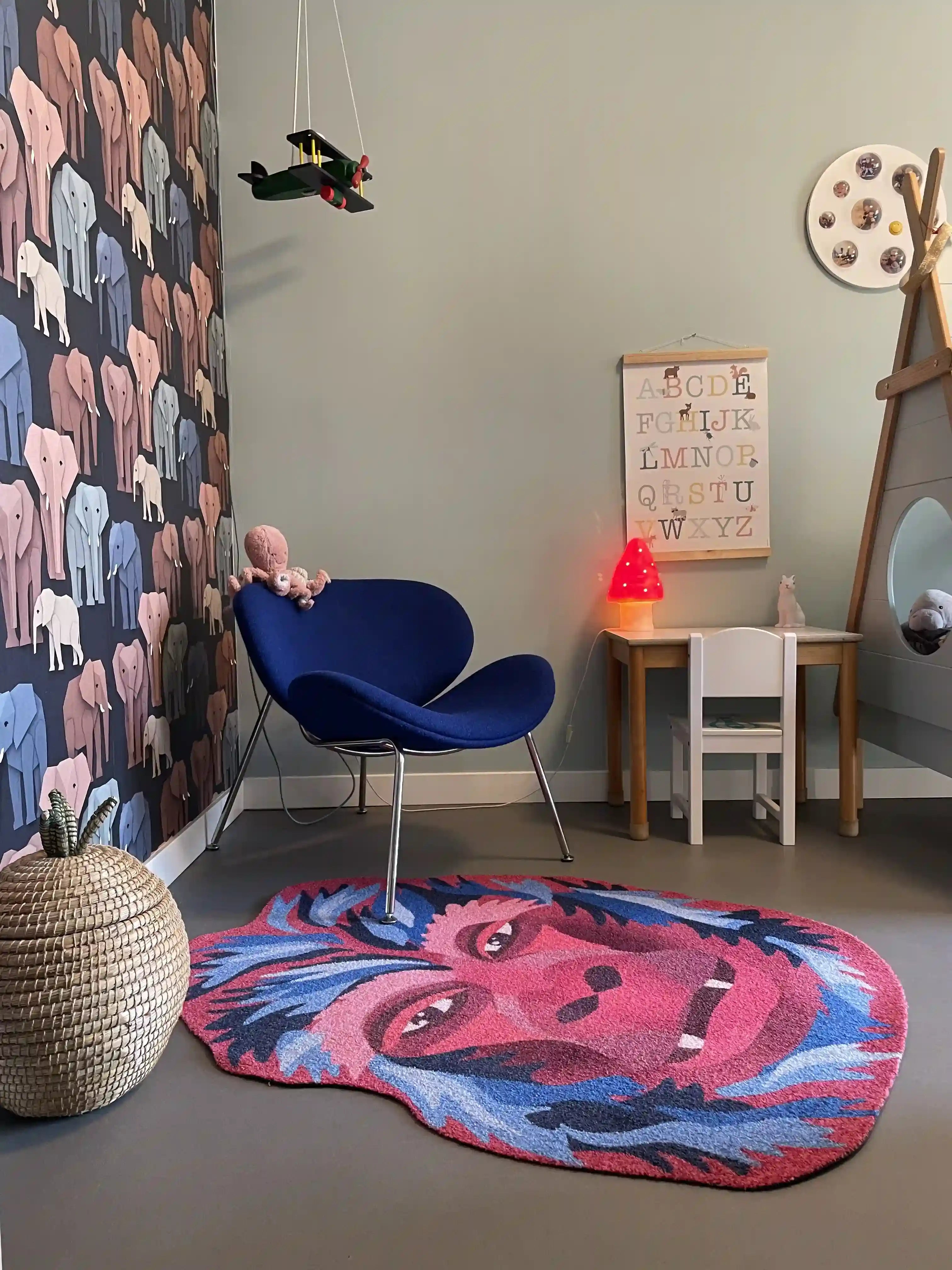 Zacht uitgesneden dierenkleed in de vorm van een gorillahoofd van Studio LilaLine – het kleed toont een krachtige, vriendelijke gorilla met een expressieve blik, uitgevoerd in diepe rood- en blauwtinten. De vorm is rond en herkenbaar, met duidelijke gelaatstrekken zoals een brede neus en zachte ogen. Een stoere en toch knusse speelplek voor op de vloer van een kinderkamer of speelhoek.