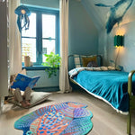 Zacht uitgesneden dierenkleed in de vorm van een koraalduivel van Studio LilaLine – deze fantasierijke vis heeft sierlijke vinnen die wijd uitstaan, in sprekende tinten groen en oranje. De visvorm is dynamisch en decoratief, met speelse strepen en zachte rondingen. Het kleed is heerlijk zacht en nodigt uit tot spelen, liggen of fantaseren in een gezellige hoek van de kinderkamer.