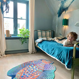 Zacht uitgesneden dierenkleed in de vorm van een koraalduivel van Studio LilaLine – deze fantasierijke vis heeft sierlijke vinnen die wijd uitstaan, in sprekende tinten groen en oranje. De visvorm is dynamisch en decoratief, met speelse strepen en zachte rondingen. Het kleed is heerlijk zacht en nodigt uit tot spelen, liggen of fantaseren in een gezellige hoek van de kinderkamer.
