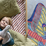 Zacht uitgesneden dierenkleed in de vorm van een nachtvlinder van Studio LilaLine – het kleed heeft uitgespreide vleugels in tinten van blauw, groen en fel oranje, met een patroon dat doet denken aan oogvormige vlekken en fijne lijnen. De vorm is symmetrisch en sierlijk, met zachte rondingen en een elegante uitstraling. Perfect om op te spelen of knus op te zitten in een kinderkamer of leeshoek.