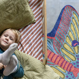 Zacht uitgesneden dierenkleed in de vorm van een nachtvlinder van Studio LilaLine – het kleed heeft uitgespreide vleugels in tinten van blauw, groen en fel oranje, met een patroon dat doet denken aan oogvormige vlekken en fijne lijnen. De vorm is symmetrisch en sierlijk, met zachte rondingen en een elegante uitstraling. Perfect om op te spelen of knus op te zitten in een kinderkamer of leeshoek.