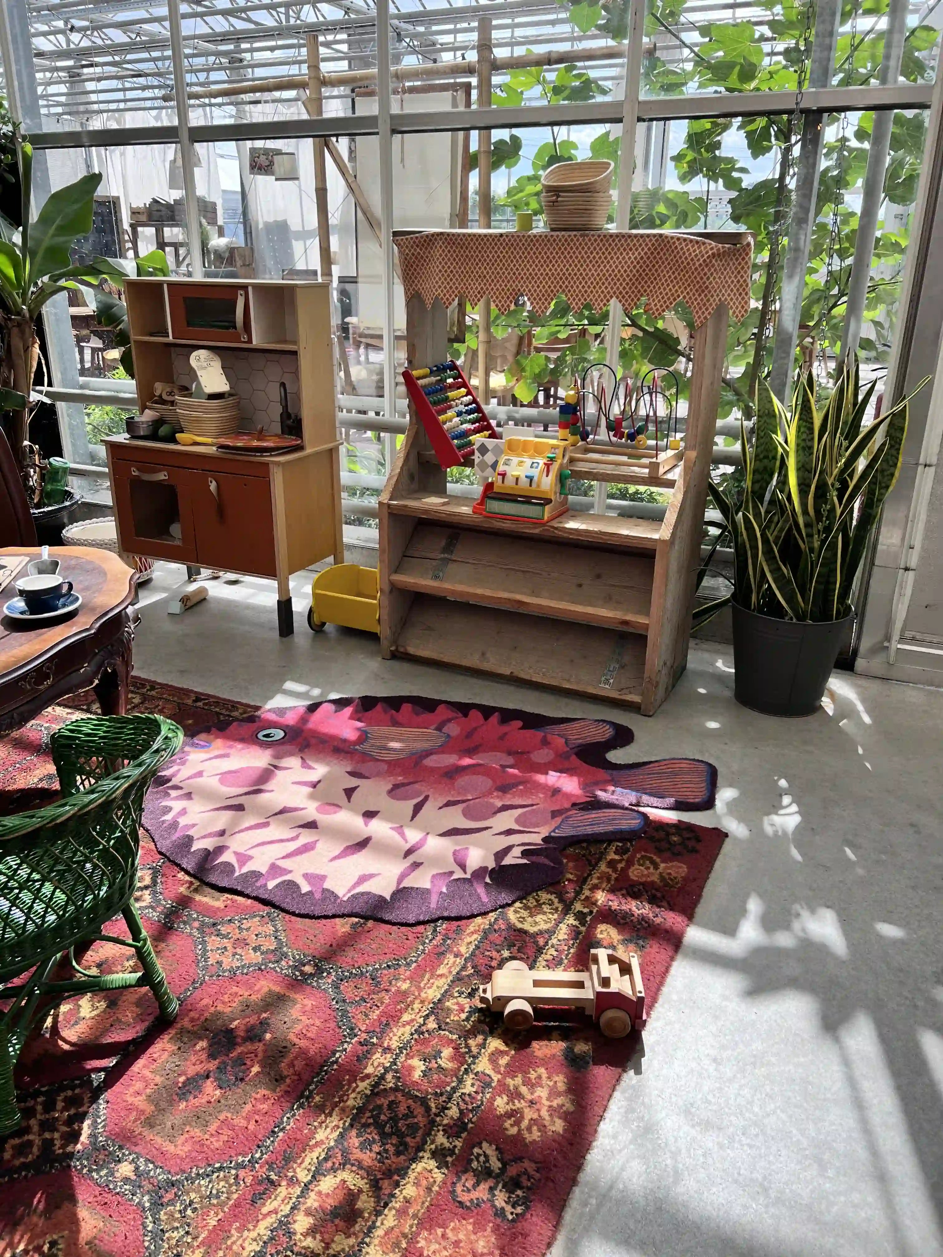 Zacht uitgesneden dierenkleed in de vorm van een kogelvis van Studio LilaLine – het kleed toont een bolvormige vis met stekelige details, in warme tinten van oranje, rood en bordeaux. De vorm is speels en herkenbaar, met grote ronde ogen en een lichte glimlach. Het oppervlak voelt zacht en knuffelig aan, ideaal om op te spelen, liggen of een boekje te lezen in een gezellige kinderhoek.