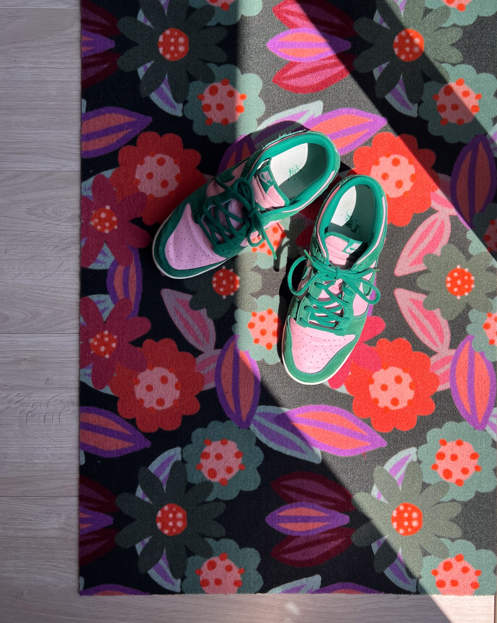 Droogloopmat en deurmat van Studio LilaLine met een speelse bloemvorm in tinten roze, oranje en groen – het ontwerp doet denken aan een vrolijk uitgestoken koekje met een knipoog naar retro bloemmotieven. De mat is slijtvast, neemt goed vocht op en zorgt voor een kleurrijke en uitnodigende entree, zowel praktisch als decoratief.